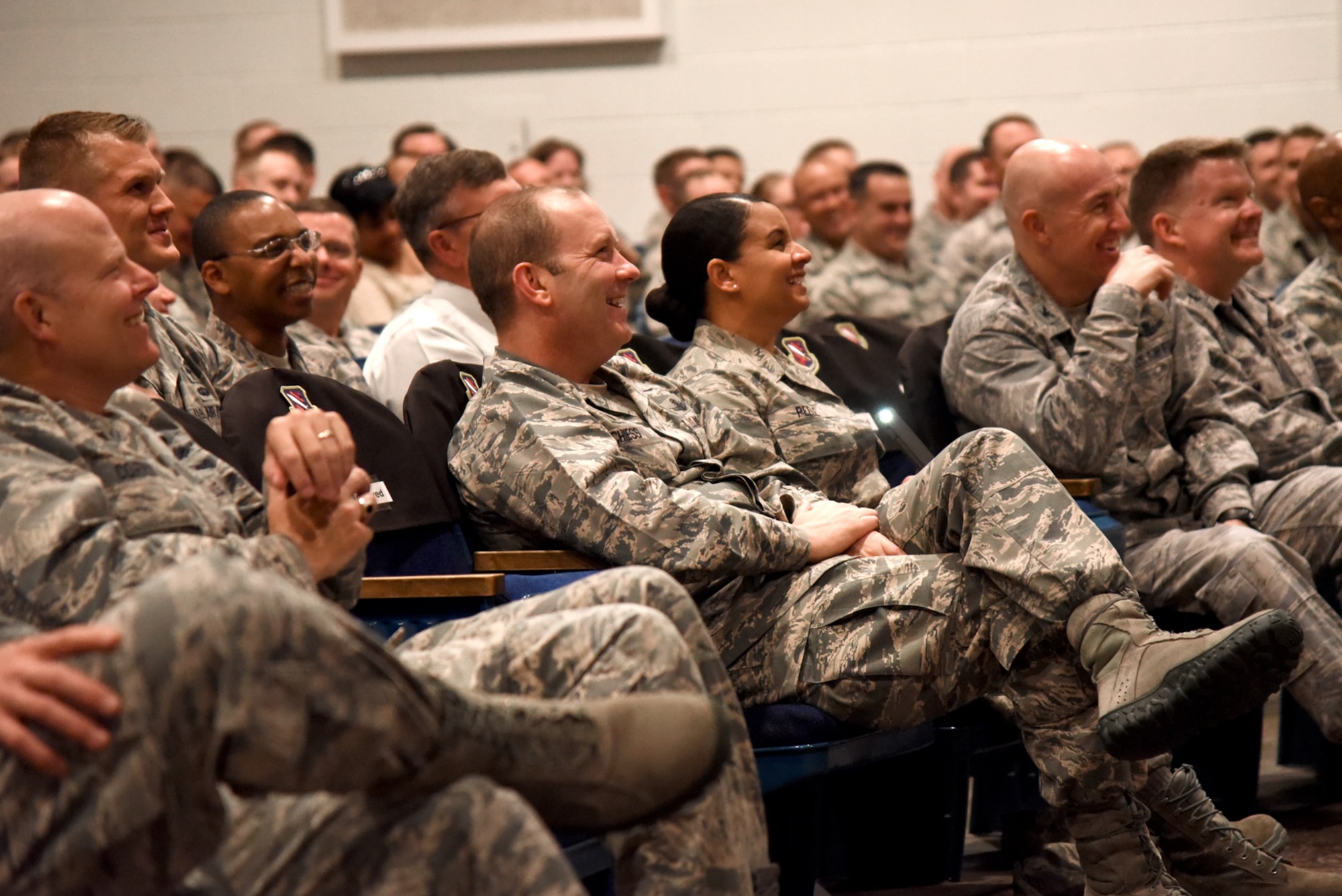 PETERSON AIR FORCE BASE, Colo. – Col. Doug Schiess, 21st Space Wing commander, and Chief Master Sgt. Idalia Peele, 21st Space Wing command chief, listen as Herschel Walker, retired NFL football player, engages Team Pete with light-hearted stories of his youth in the base auditorium at Peterson Air Force Base, Colo. on June 8, 2016. Walker admitted to being beaten as a child, which led him to begin workouts that eventually consisted of 5,000 push-ups and 5,000 sit-ups daily. (U.S. Air Force photo by Airman 1st Class Dennis Hoffman)