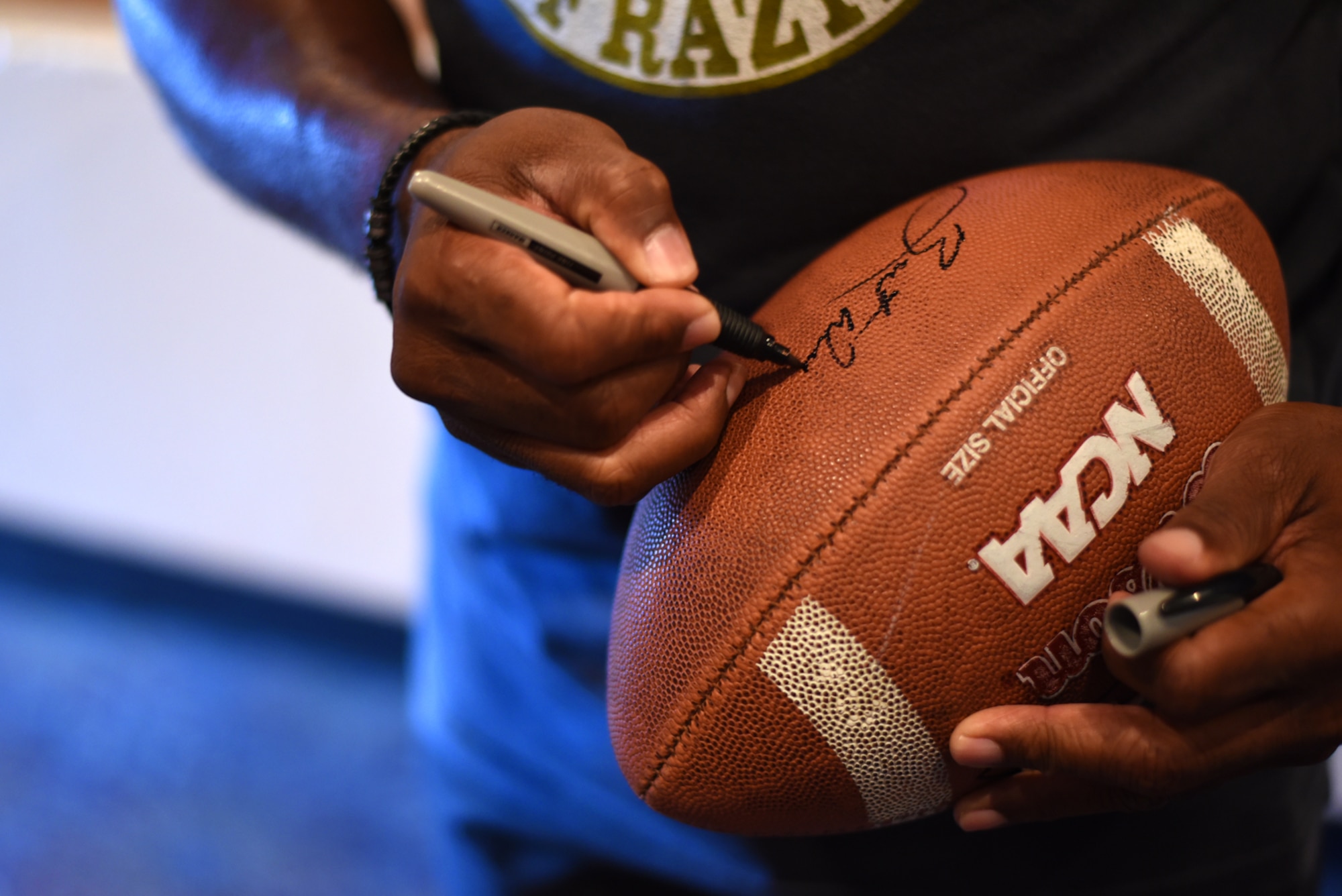 PETERSON AIR FORCE BASE, Colo. – Herschel Walker, retired NFL football player, signs autographs for Team Pete in the base auditorium at Peterson Air Force Base, Colo. on June 8, 2016. Walker was elected to the College Football Hall of Fame in 1999 and is widely regarded as one of college football's greatest players. (U.S. Air Force photo by Airman 1st Class Dennis Hoffman)