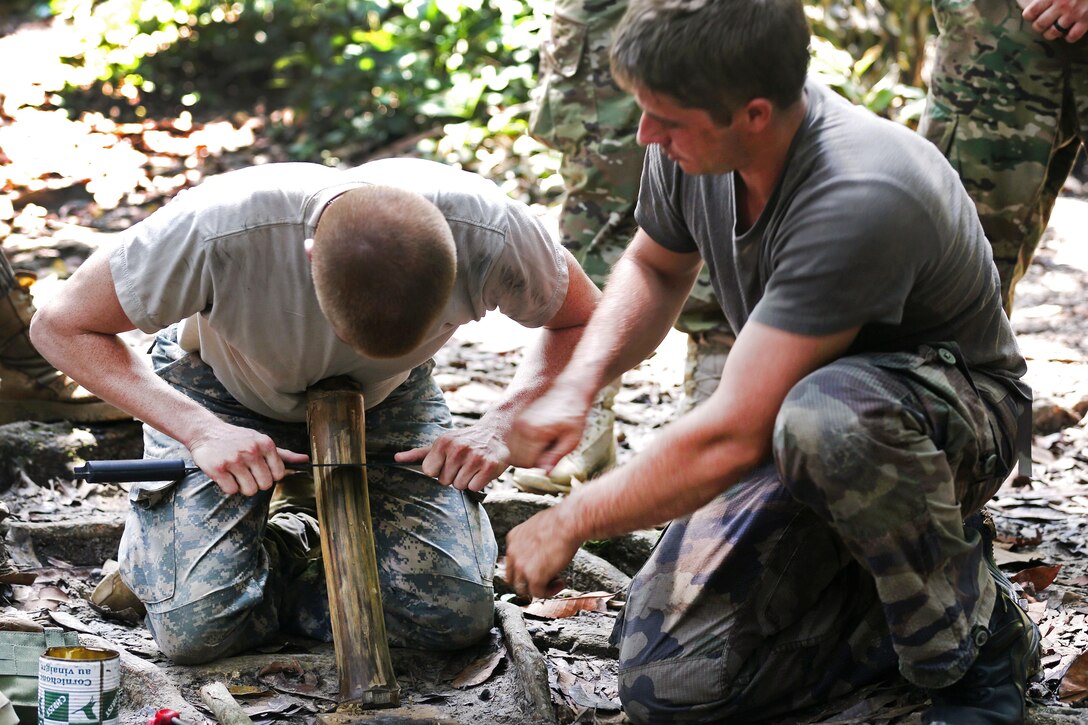 A French army sergeant, right, assigned to the jungle warfare school in Gabon, helps a U.S. soldier shave bamboo to start a fire at the school, June 6, 2016, as part of Central Accord 2016. Army photo by Sgt. Henrique Luiz de Holleben