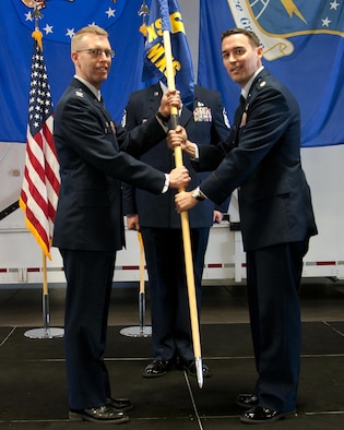 Maj. Grant Fowler, 790th Maintenance Squadron commander, takes the 790th MXS guidon from Col. Greg Buckner, 90th Maintenance Group commander, during a change-of-command ceremony June 13, 2016, inside the Maintenance High Bay on F.E. Warren Air Force Base, Wyo. The passing of the guidon stems from military tradition, with the guidon symbolizing a flag that soldiers would rally behind during battles. (U.S. Air Force photo By Airman 1st Class Malcolm Mayfield)