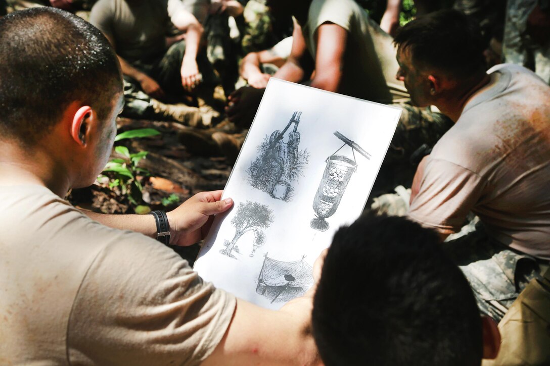 A U.S. soldier looks at illustrations of methods for collecting water at the French jungle warfare school in Gabon, June 6, 2016. Army photo by Spc. Yvette Zabala-Garriga