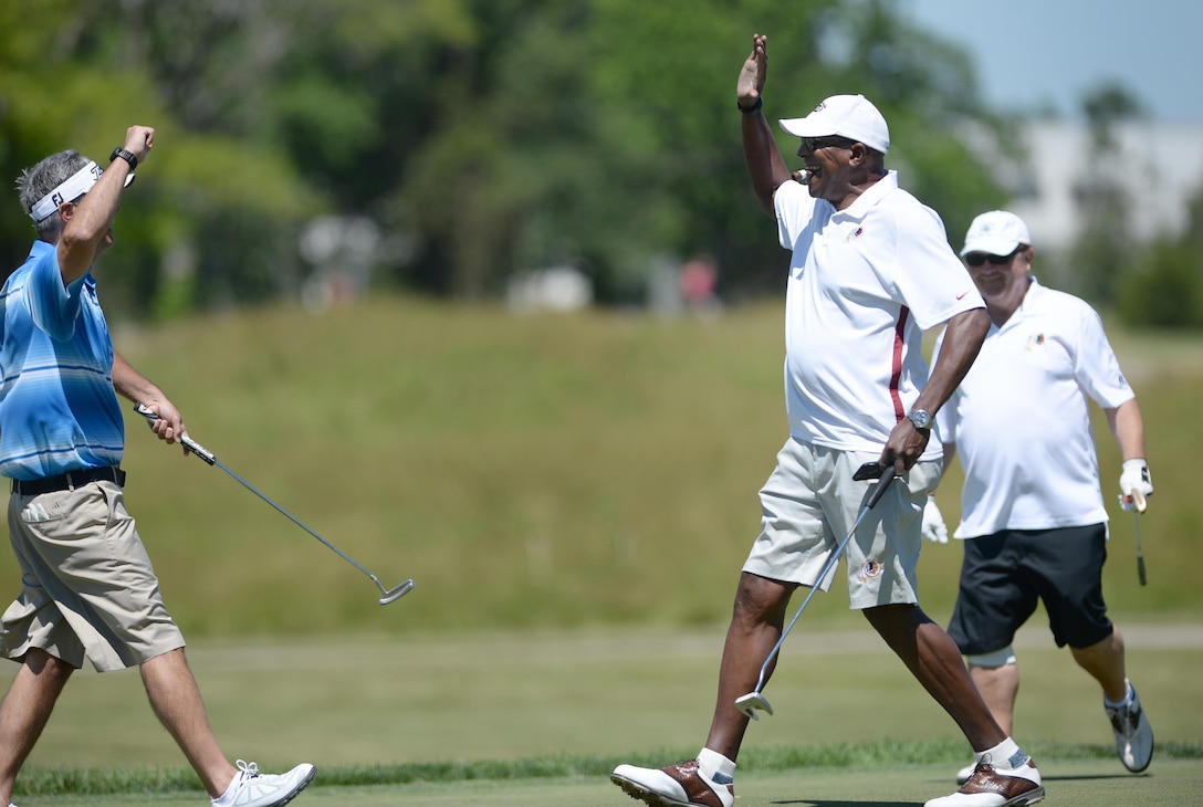 Rick “Doc” Walker, foreground right, an ESPN 980 broadcaster and former Washington Redskin, congratulates a teammate after a successful putt during the 9th Annual ESPN 980 True Heroes Charity Golf Tournament to benefit the Purple Heart Foundation at the 1757 Golf Club in Sterling, Va., DoD photo by Marvin D. Lynchard 