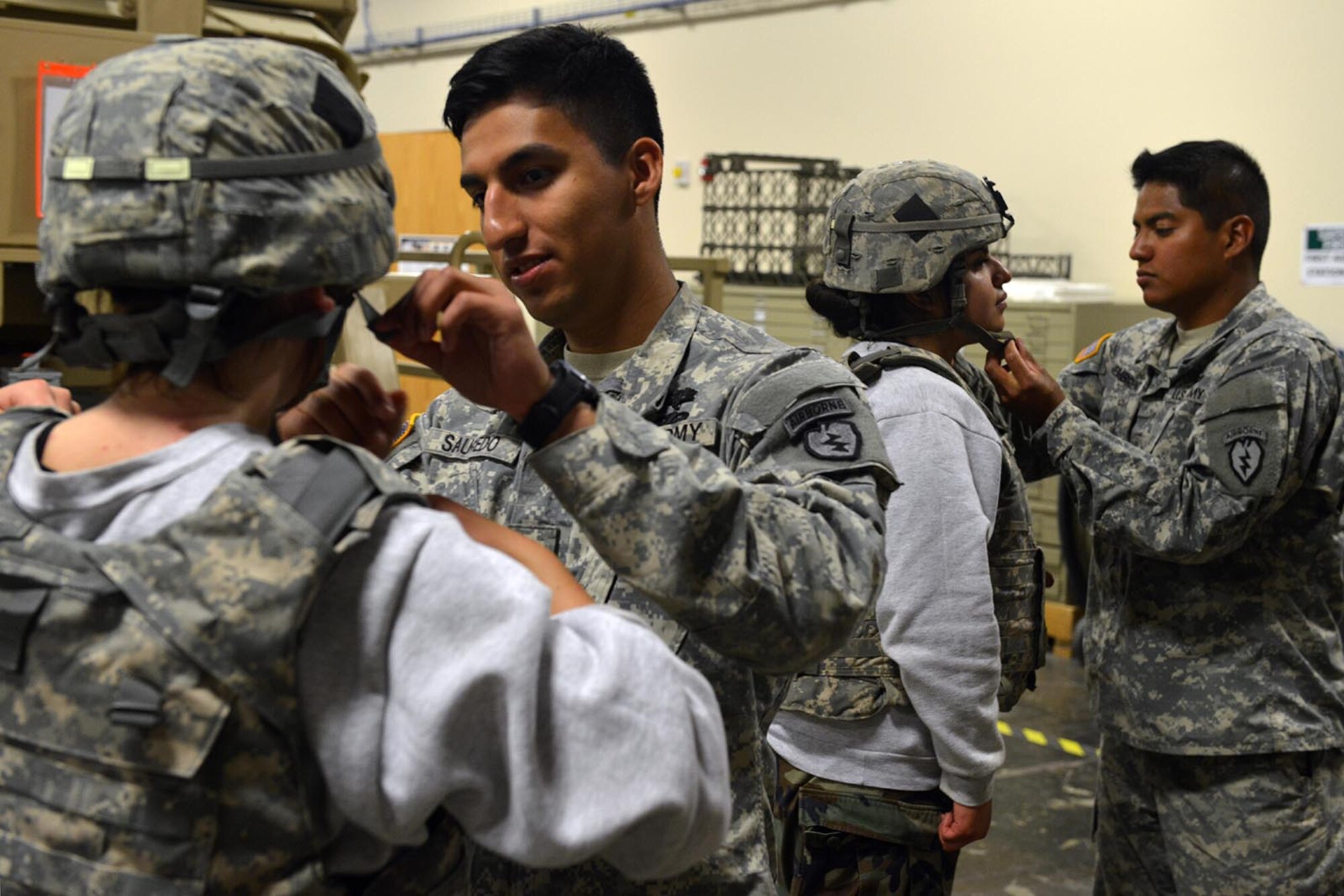 Specialist Mark Saucedo, healthcare specialist, and Pfc. Erick Membreno, gunner, with 1st Battalion, 501st Parachute Infantry Regiment, 4th Infantry Brigade Combat Team (Airborne), 25th Infantry Division, assist Alaska School District Junior ROTC cadets fasten safety gear at the Humvee Egress Assistance Trainer on Joint Base Elmendorf-Richardson, Alaska, June 8, 2016. Cadets were able to experience a simulated Humvee rollover scenario in the trainer. (U.S. Air Force photo by Airman 1st Class Javier Alvarez) 