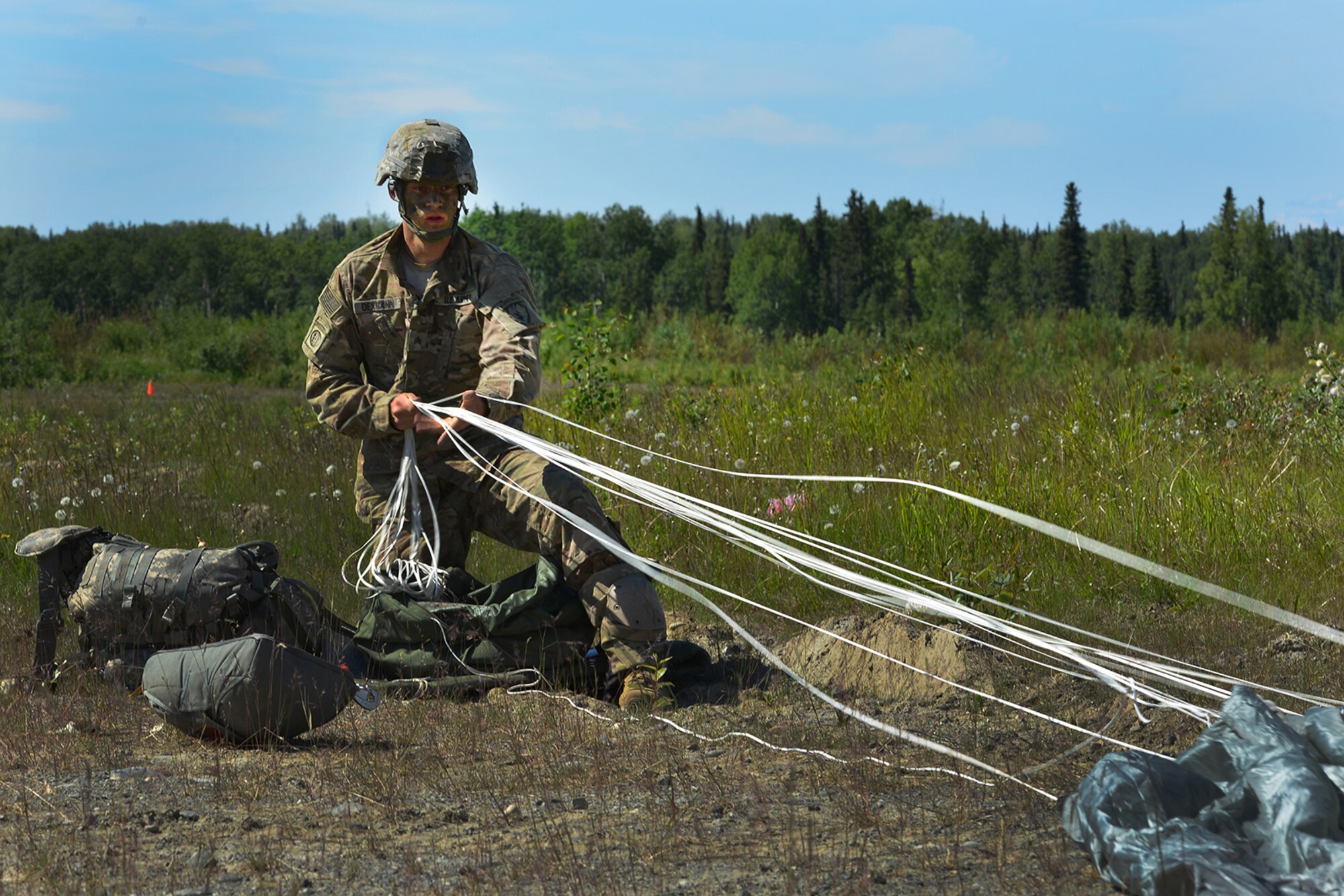 Sgt. Andrew Oexmann, assigned to the 4th Infantry Brigade Combat Team (Airborne), 25th Infantry Division, U.S. Army Alaska, recovers his parachute while executing an airborne proficiency operation, and coordination for follow-on training at Joint Base Elmendorf-Richardson, Alaska, June 9, 2016, during Exercise Arctic Aurora. Arctic Aurora is a yearly bilateral training exercise involving elements of the Spartan Brigade and the JGSDF, which focuses on strengthening ties between the two by executing combined small unit airborne proficiency operations and basic small arms marksmanship. (U.S. Air Force photo by Airman 1st Class Valerie Monroy)