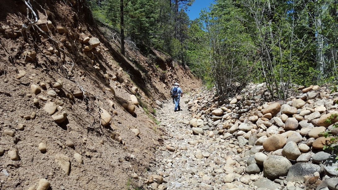 Memphis District engineers survey a section of the Chamisal Acequia to design a solution that will help keep the acequia flowing and clear of loose cobbles and boulders.