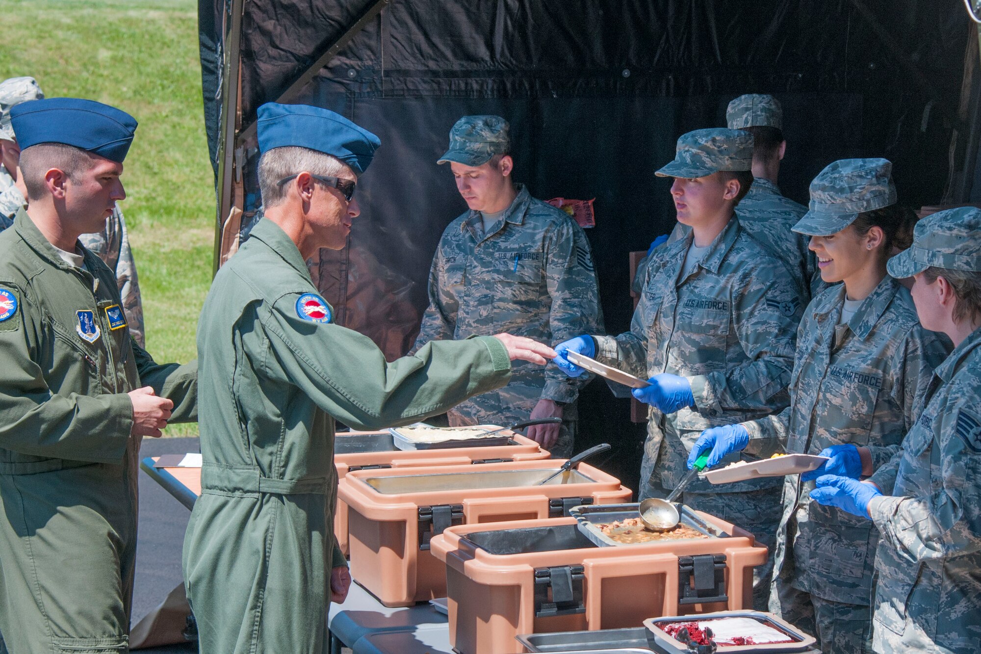 Master Sgt. Scott Miller (left), a loadmaster at the 167th Airlift Wing in Martinsburg, W.Va., receives his lunch from Airman 1st Class Shelby Alford, a services personnel at the 167th AW, June 10, 2016. Services took advantage of super drill to put up the Single Pallet Expeditionary Kitchen (SPEK). When the SPEK is fully put up it can seat 750 people. The food that is prepared comes in a unit group ration (UGR) that feeds 25 people. The UGR comes in three boxes and contains entrees, starch, paper products, and utensils. . (U.S. Air National Guard photo by Staff Sgt. Jodie Witmer)