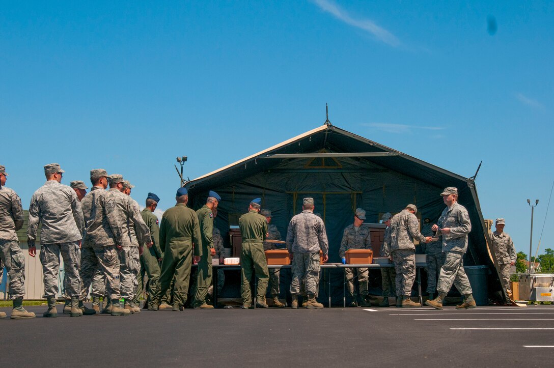 Unit members at the 167th Airlift Wing in Martinsburg, W.Va. stood in line for lunch at the Single Pallet Expeditionary Kitchen (SPEK) that was put up by services members at super drill, June 10, 2016. The SPEK can be set up by 8 people in about 2 hours.  The apparatus that is used to heat the food is called a tray ration heater that is heated by a babington burner powered by diesel. (U.S. Air National Guard photo by Staff Sgt. Jodie Witmer)