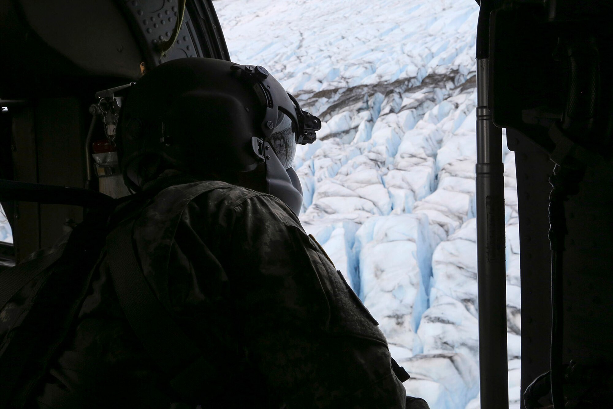 Alaska Army National Guard UH-60 Black Hawk helicopter crew chief, Sgt. Sonny Cooper, assigned to the 1st Battalion, 207th Aviation Regiment, surveys a potential landing site on Colony Glacier near Anchorage, Alaska, June 4, 2016. In November 1952, a U.S. Air Force C-124 Globemaster II crashed into Mt. Gannett in the Chugach Mountains near Anchorage killing all of the 52 servicemembers on board. Every summer since 2012, Alaskan Command, the Alaska National Guard, Air Force Mortuary Affairs Operations, U.S. Army Alaska, 673d Air Base Wing, 3d Wing and Detachment 1, 66 Training Squadron personnel support the joint effort of Operation Colony Glacier, a mission to recover any human remains and remove debris. (U.S. Air Force photo/Alejandro Pena)