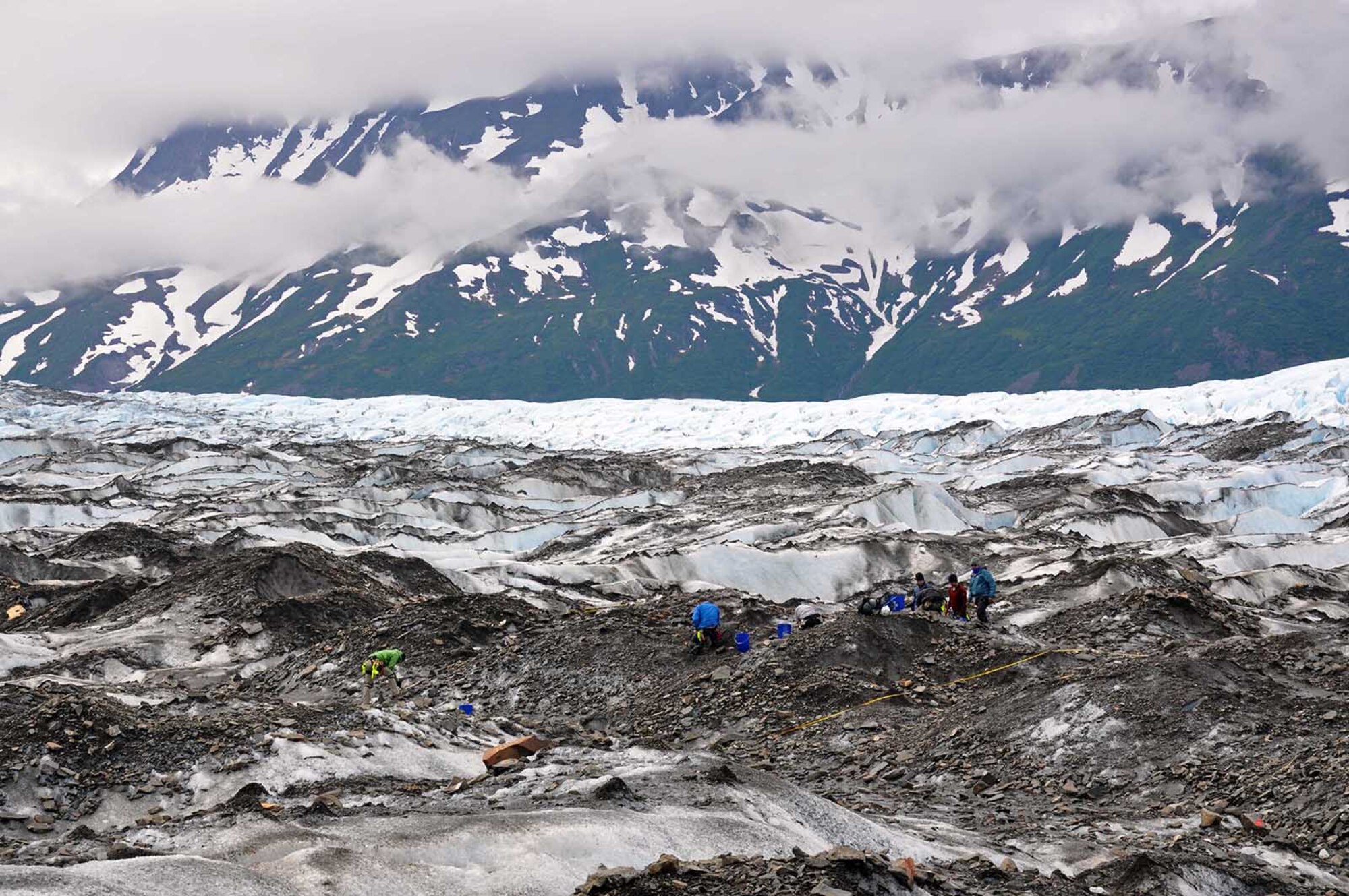 Team members working as part of Operation Colony Glacier comb through remains and wreckage June 13, 2016 on Colony Glacier near Anchorage, Alaska. Operation Colony Glacier is a mission to recover human remains and remove debris from a 1952 crash of a U.S. Air Force C-124 Globemaster II on the glacier with 52 servicemembers on board. The recovery effort has taken place every summer since 2012 by personnel from Alaskan Command, the Alaska National Guard, Air Force Mortuary Affairs Operations, U.S. Army Alaska, 673d Air Base Wing, 3d Wing and Detachment 1, 66 Training Squadron. (U.S. Air Force photo/Capt. Anastasia Wasem)