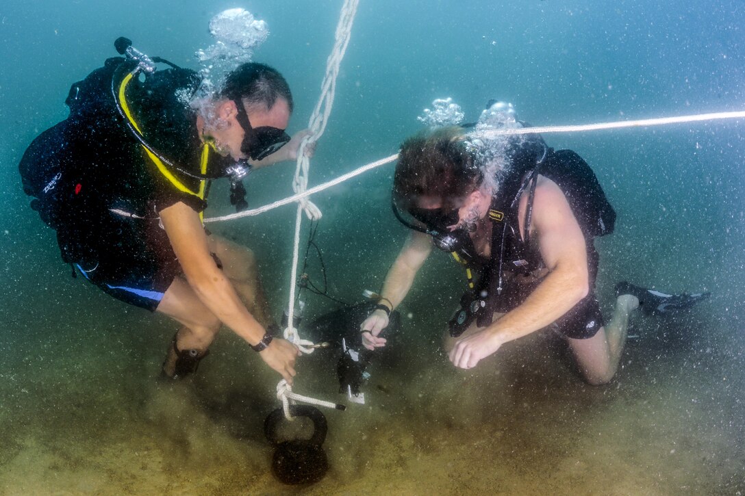 A U.S. sailor, right, instructs a Vietnamese sailor during a search as part of an underwater ordnance removal training program in Nha Trang, Vietnam, June 10, 2016. The program is designed to help the Vietnam navy handle unexploded underwater mines. Navy photo by Petty Officer 3rd Class Alfred A. Coffield