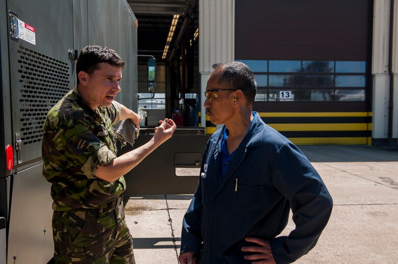 Romanian Land Forces Warrant Officer Bogden Cosma, Heavy Airlift Wing vehicle maintenance NCO-in-charge assigned to Papa Air Base, Hungary, left, speaks with Pedro Sagisi, the aircraft deicer qualification training course instructor, during the lab portion of the course at the European Transportation Training Center on Spangdahlem Air Base, Germany, June 9, 2016. The training course took 10 business days, subjecting students to the academics and hands-on portion of becoming experts in maintaining the deicer truck. (U.S. Air Force photo by Airman 1st Class Timothy Kim/Released)