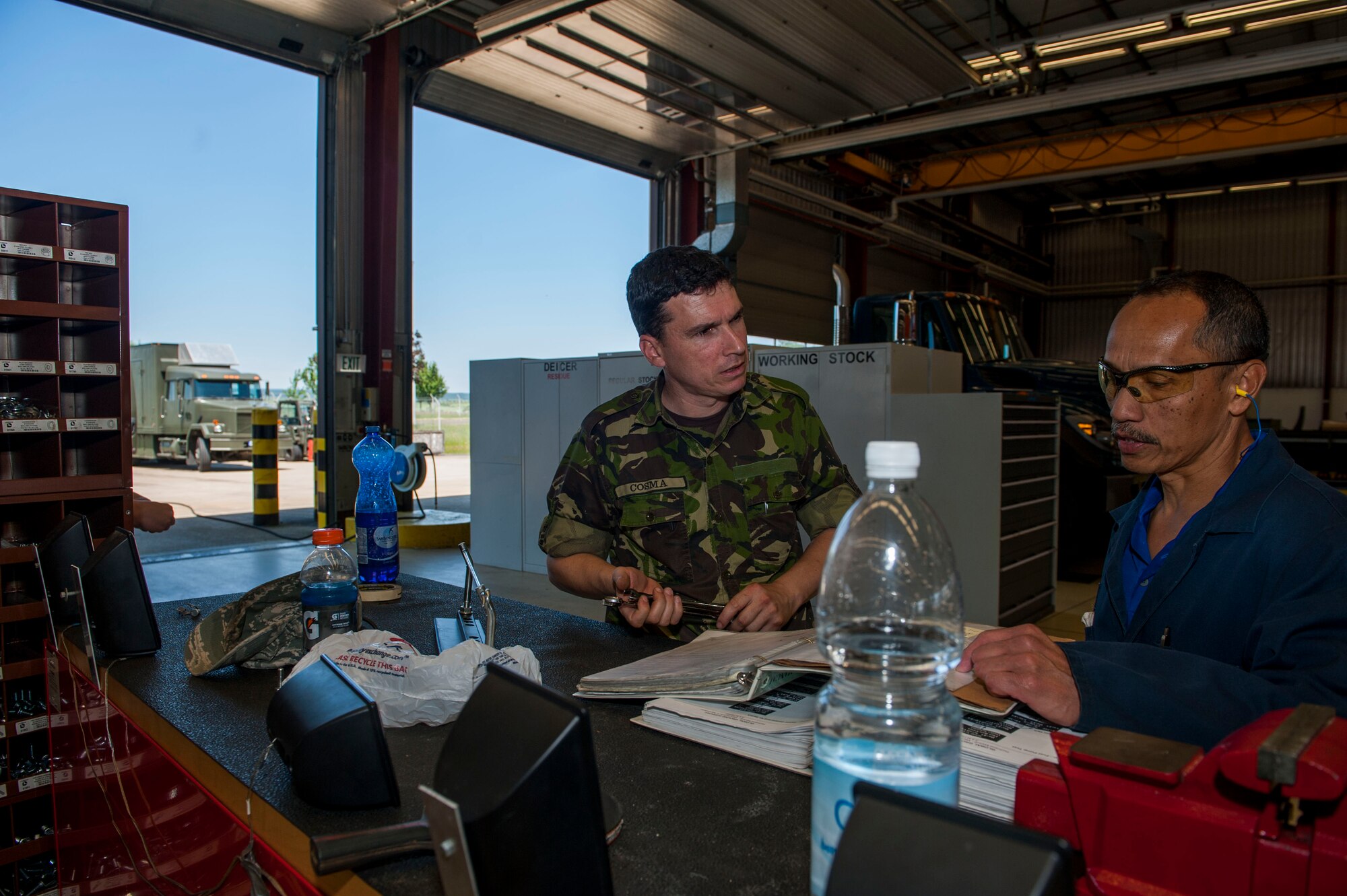 Romanian Land Forces Warrant Officer Bogden Cosma, Heavy Airlift Wing vehicle maintenance NCO-in-charge assigned to Papa Air Base, Hungary, left, speaks with Pedro Sagisi, the aircraft deicer qualification training course instructor, during the course at the European Transportation Training Center on Spangdahlem Air Base, Germany, June 9, 2016. Cosma supervises and manages a fleet of 35 ground transportation and flight line support vehicles that enable strategic airlift capabilities in Hungary. (U.S. Air Force photo by Airman 1st Class Timothy Kim/Released)