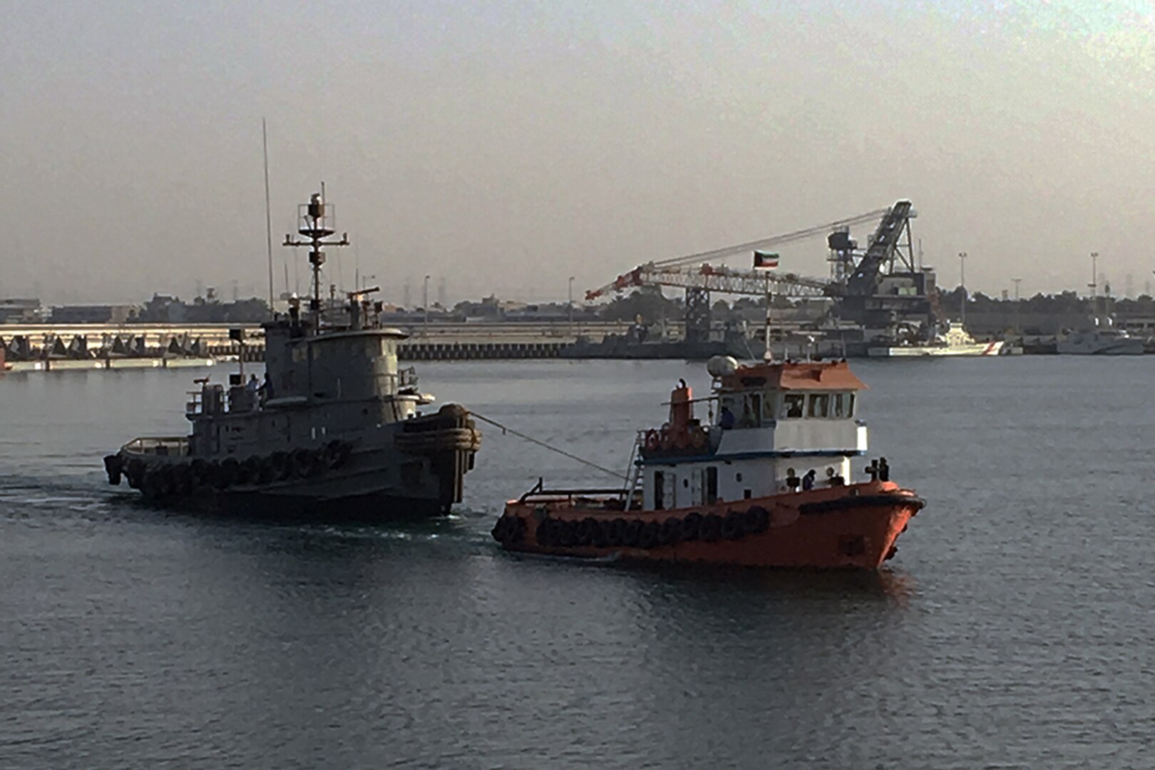 A contract tug begins its 12-hour journey from Kuwait Naval Base to the port of Doha, Qatar, with the retired Army tugboat in tow.