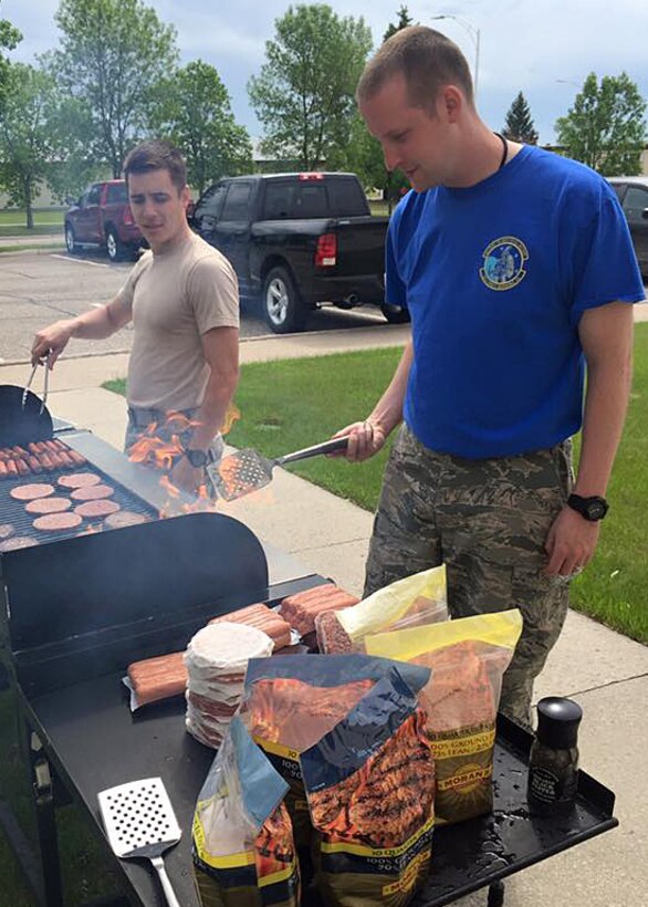 Airmen from the 10th Space Warning Squadron barbeque food for their unit picnic during Arbor Day festivities at Cavalier Air Force Station, N.D. on June 3, 2016. They celebrated the importance of Arbor Day by planting trees and flowers and participating in a Tree City U.S.A. presentation. (Courtesy photo)