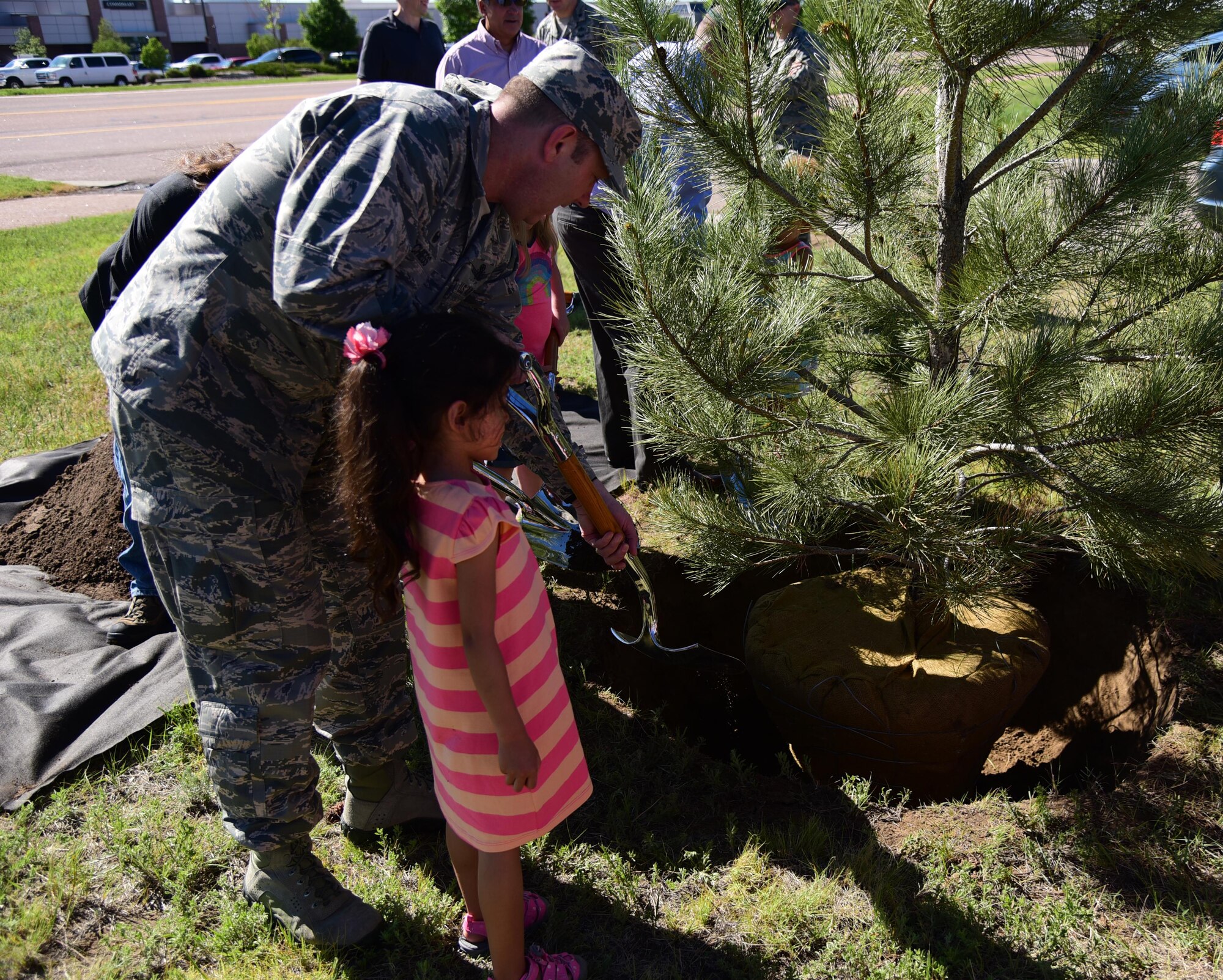 Col. Douglas Schiess, 21st Space Wing commander, assists Emmalyn Curristine in planting two new trees at Peak View Park in celebration of Arbor Day at Peterson Air Force Base, Colo., June 14, 2016. Planting trees is a way to combat climate change, in one year an acre of mature trees can absorb the amount of carbon dioxide produced by a vehicle driving 26,000 miles. (U.S. Air Force photo by Staff Sgt. Amber Grimm)