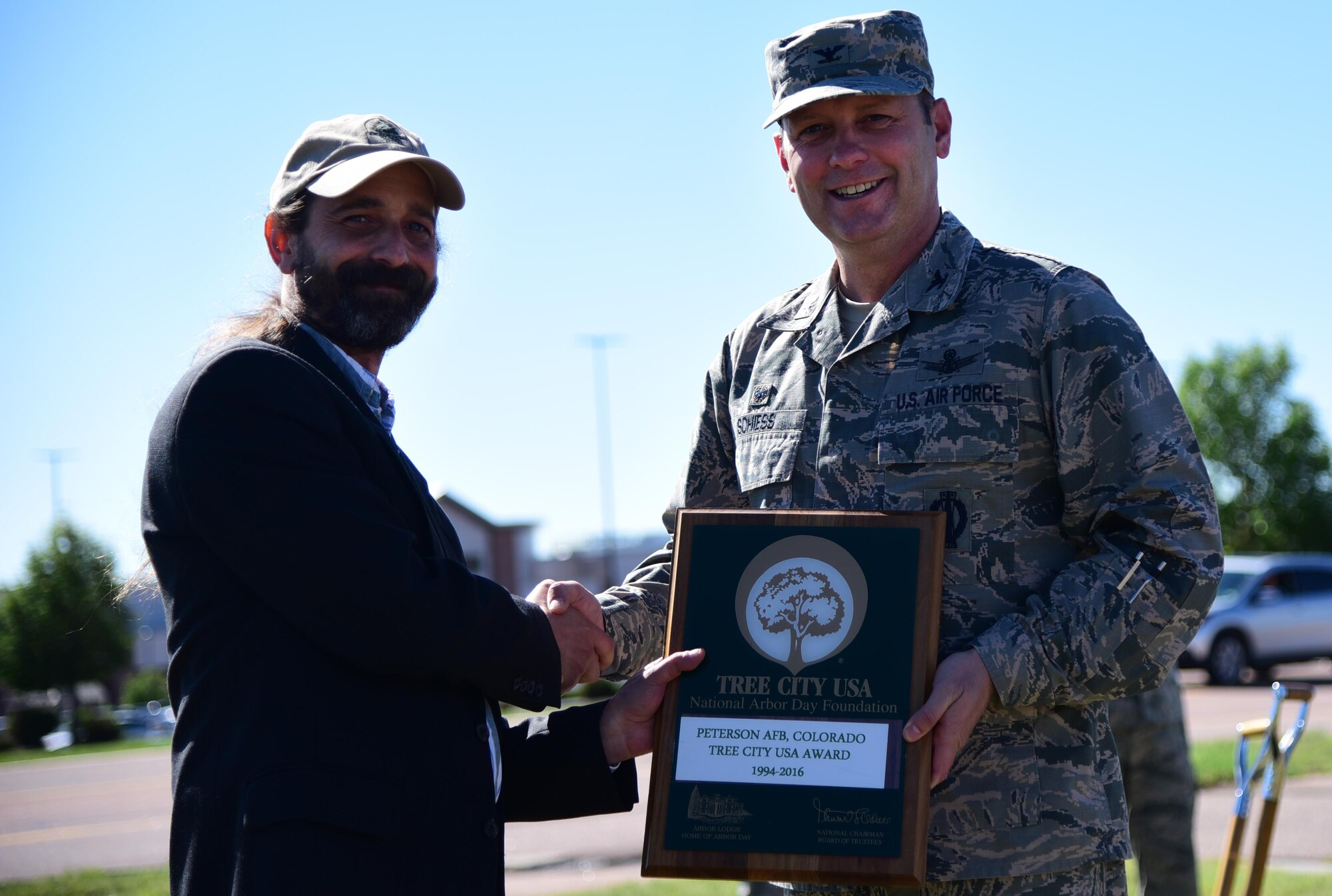 Andy Schlosberg, Arbor Day Foundation, presents Col. Douglas Schiess, 21st Space Wing commander, with the Tree City USA Growth Award recognizing excellence in urban forestry management at Peterson Air Force Base, Colo., June 14, 2016. This was the 22nd consecutive year Peterson received the Tree City Award for adhering to the core standards of sound urban forestry management. (U.S. Air Force photo by Staff Sgt. Amber Grimm)
