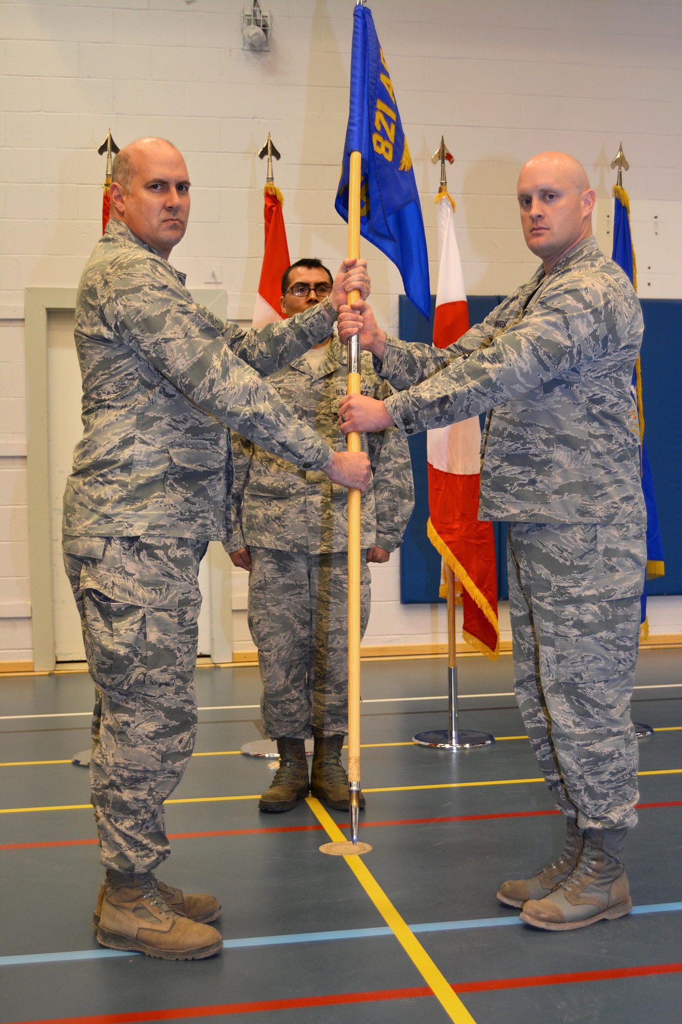 THULE AIR BASE, Greenland - Col. Stuart Pettis, 821st Air Base Group commander, passes the 821st Security Forces Squadron guidon to Maj. Brett Skates, incoming 821st SFS commander, during the change of command ceremony May 23, 2016 at base fitness center on Thule Air Base, Greenland. Before his current assignment, Skates was the operations officer at Offutt Air Force Base, Neb., and deployed multiple times in support of Operations Iraqi Freedom and Enduring Freedom. (Courtesy photo)
