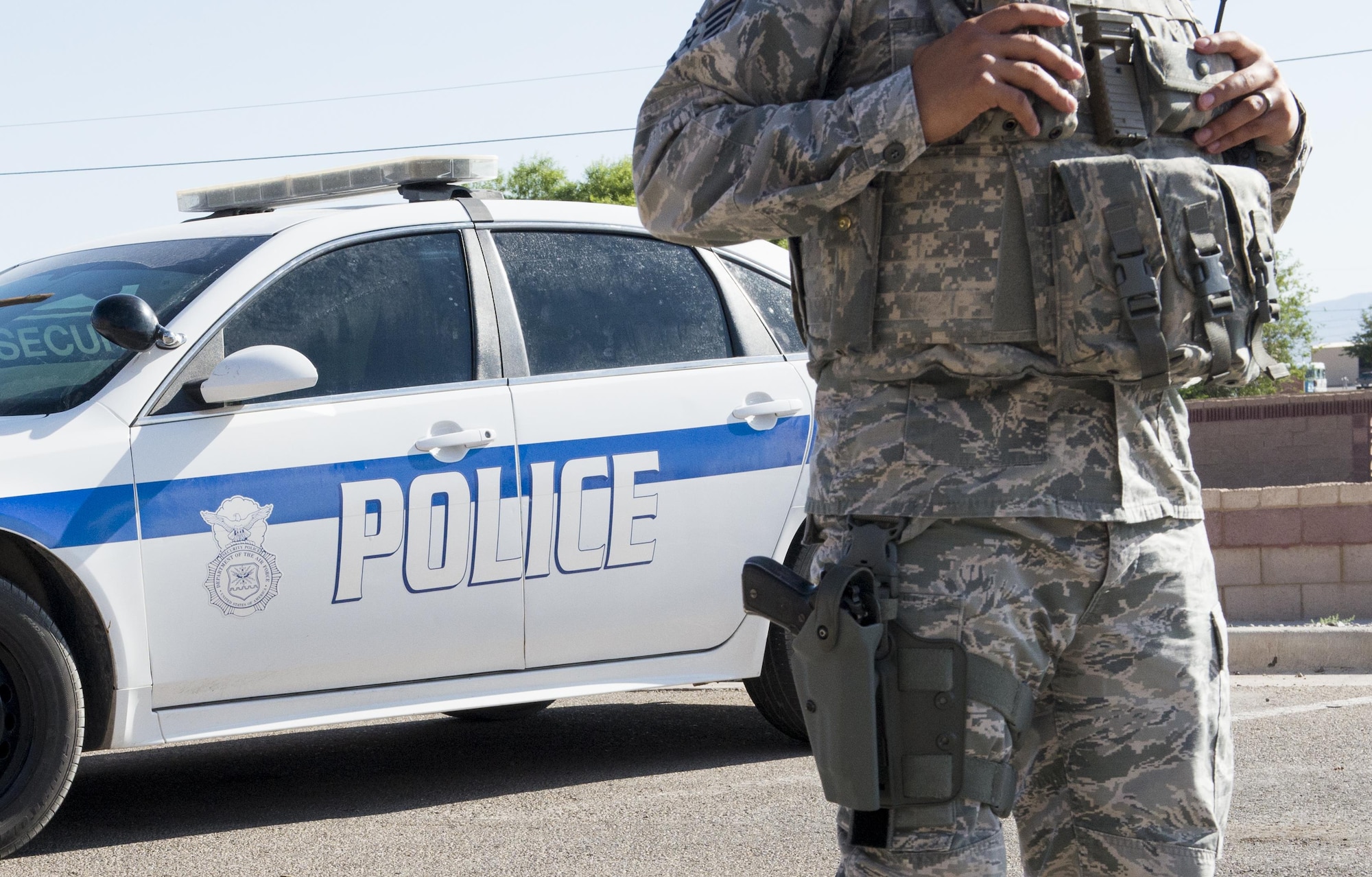 Staff Sgt. Agustin with the 49th Security Forces Squadron at Holloman Air Force Base, N.M., stands in front of his patrol car June 15. Since April 25, the 49th SFS has authorized selected personnel to be able to carry a concealed weapon while off duty and out of uniform. These changes are not the result of a direct threat, but address the everyday possibility of an active shooter incident occurring. (Last names are withheld due to operational constraints. U.S. Air Force photo by Airman 1st Class Randahl J. Jenson)    