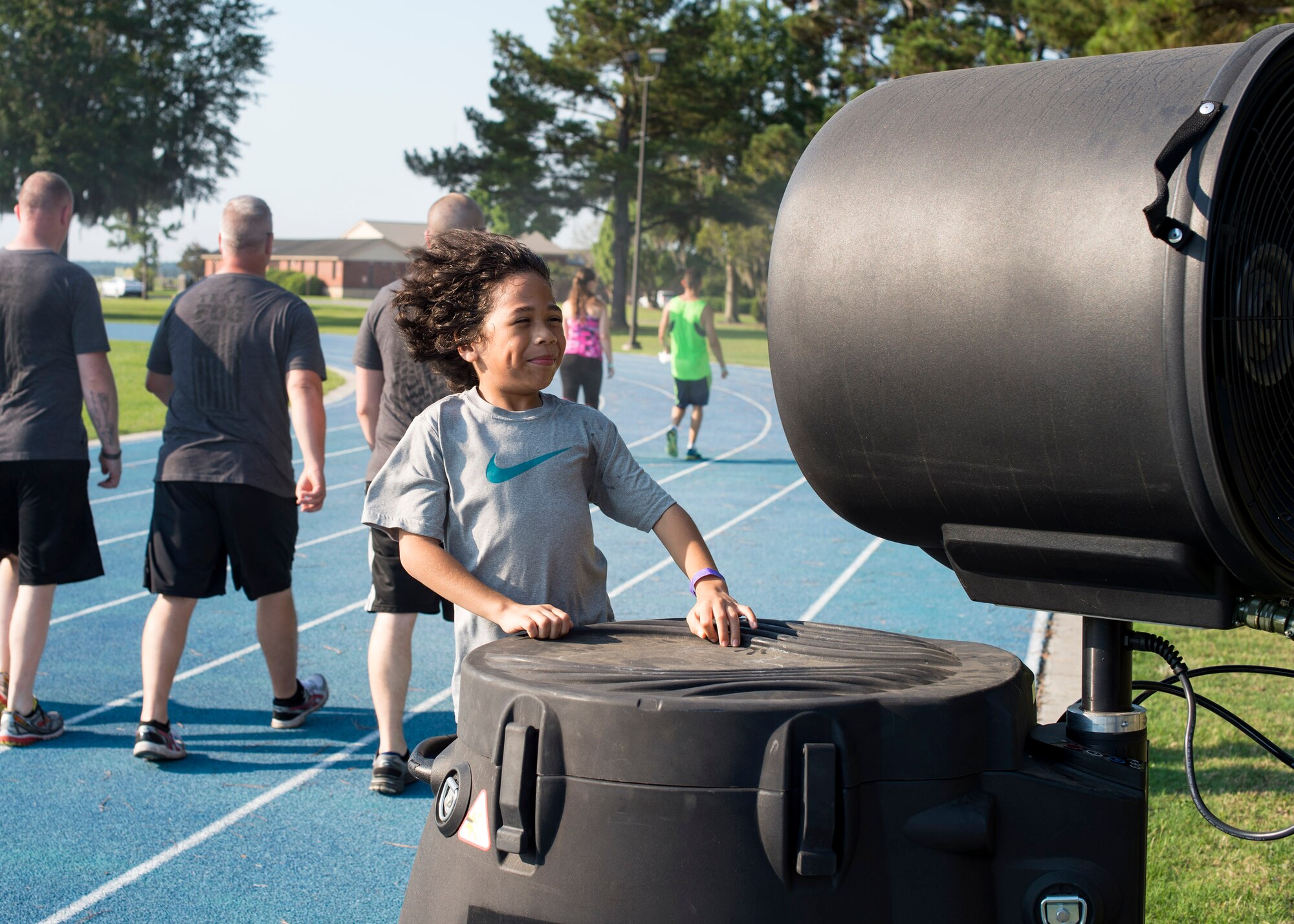 Cameron Bustamante, son of U.S. Air Force Tech. Sgt. Don Bustamante, 372nd Training Squadron A-10 avionics instructor, stands in front of a misting fan during the Tiger Run, June 11, 2016, at Moody Air Force Base, Ga. A misting fan, a giant conventional fan, water, shaved ice and wet towels were available to help participants keep cool. (U.S. Air Force photo by Airman 1st Class Janiqua P. Robinson/Released)