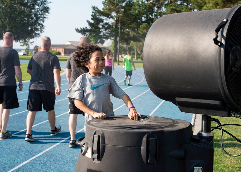 Cameron Bustamante, son of U.S. Air Force Tech. Sgt. Don Bustamante, 372nd Training Squadron A-10 avionics instructor, stands in front of a misting fan during the Tiger Run, June 11, 2016, at Moody Air Force Base, Ga. A misting fan, a giant conventional fan, water, shaved ice and wet towels were available to help participants keep cool. (U.S. Air Force photo by Airman 1st Class Janiqua P. Robinson/Released)