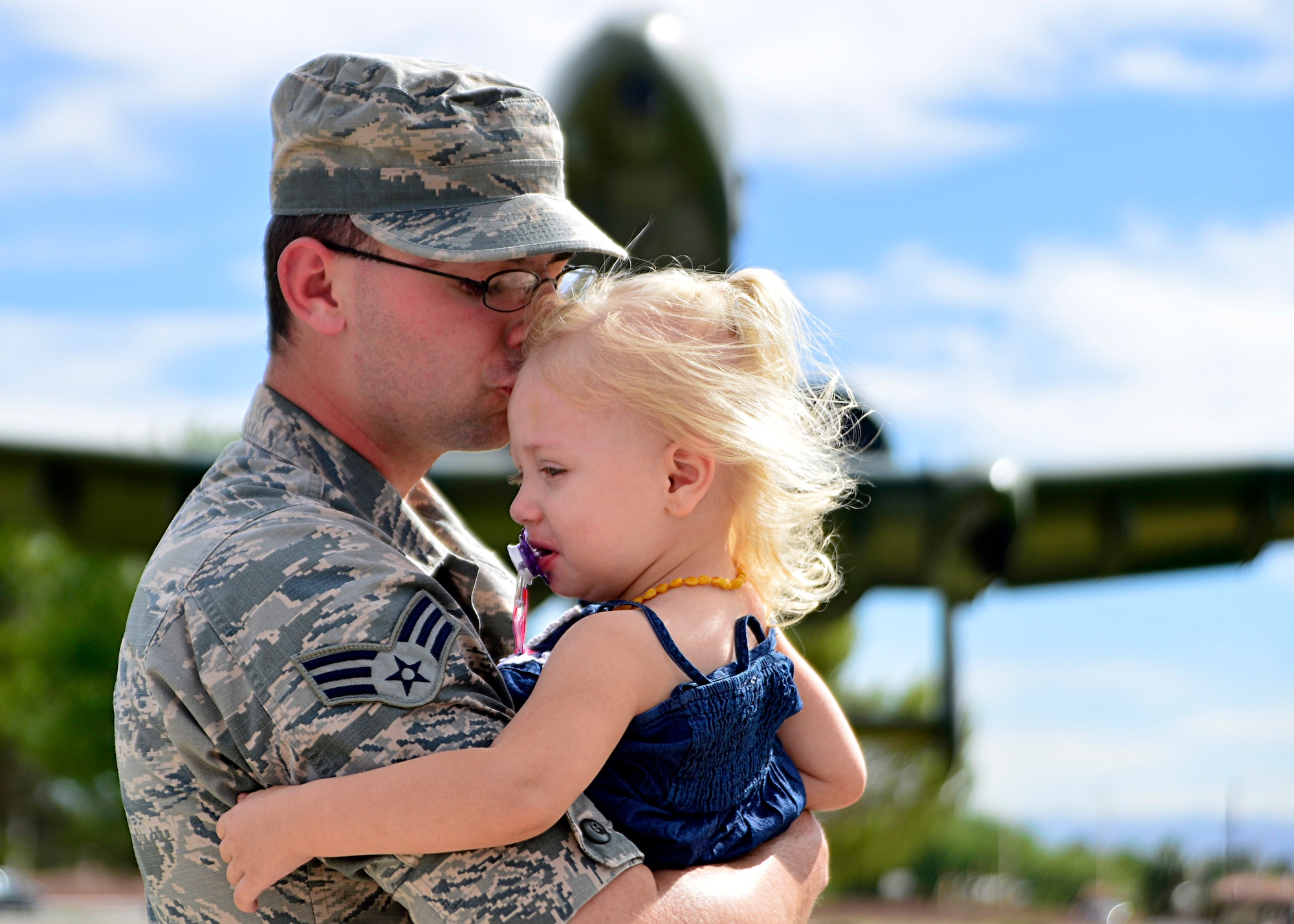 Senior Airman Christian Clauson, a 432nd Wing/432nd Air Expeditionary Wing photojournalist, kisses his daughter, Francesca, 2, at Nellis Air Force Base, Nev., June 9, 2016. Christian, who grew up as a military child, reflects on his transition from military child to military father. (U.S. Air Force photo/Tech. Sgt. Nadine Barclay)