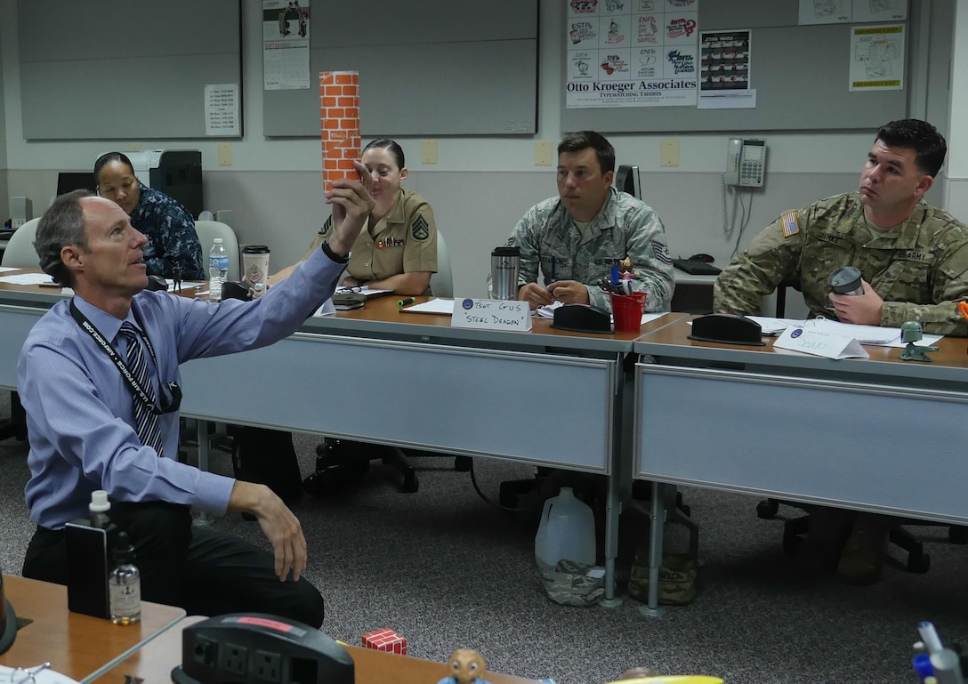 Wes Ellenburg, Instructor Training Course instructor, uses card board building blocks to teach the Instruction Systems Design process at the Defense Information School, Fort George G. Meade, Md., Sept. 11, 2015. The course focuses on the basics of developing lesson plans, creating an active learning environment and delivering content in an engaging way.