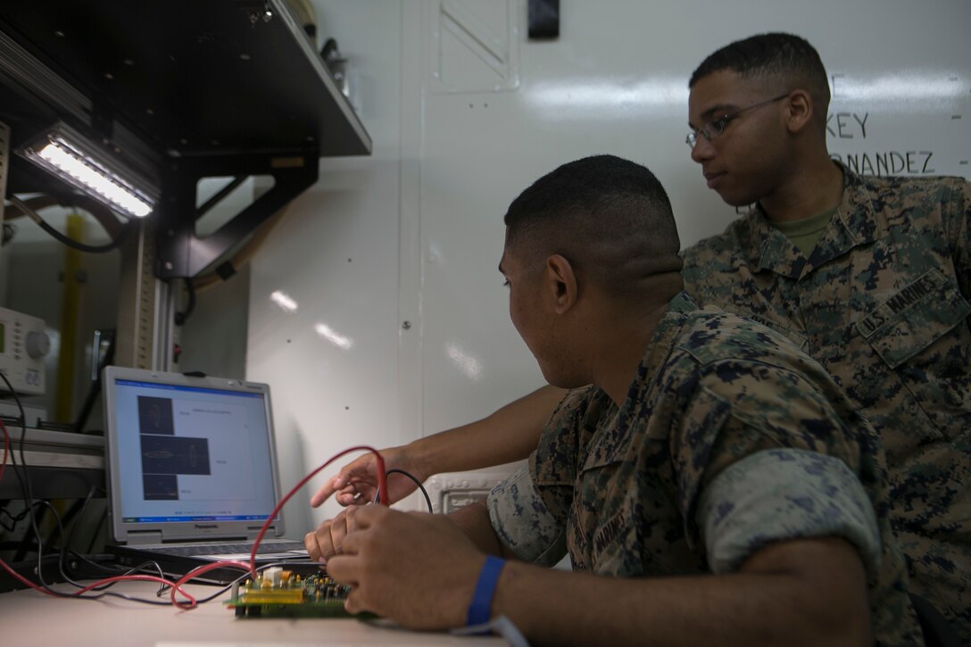 Cpl. Derek Poe instructs Lance Cpl. Joshua Lowry on Camp Courtney, Okinawa, Japan, June 2, 2016. Lowry is currently diagnosing a faulty circuit card. Poe is a Dequincy, Lousiana, native, and section chief for the miniature/ micro-miniature section for Maintenance Platoon, Communications Company, Headquarters Battalion, 3rd Marine Division, III Marine Expeditionary Force. (U.S. Marine Corps photo by Cpl. Tyler Ngiraswei/ Released)