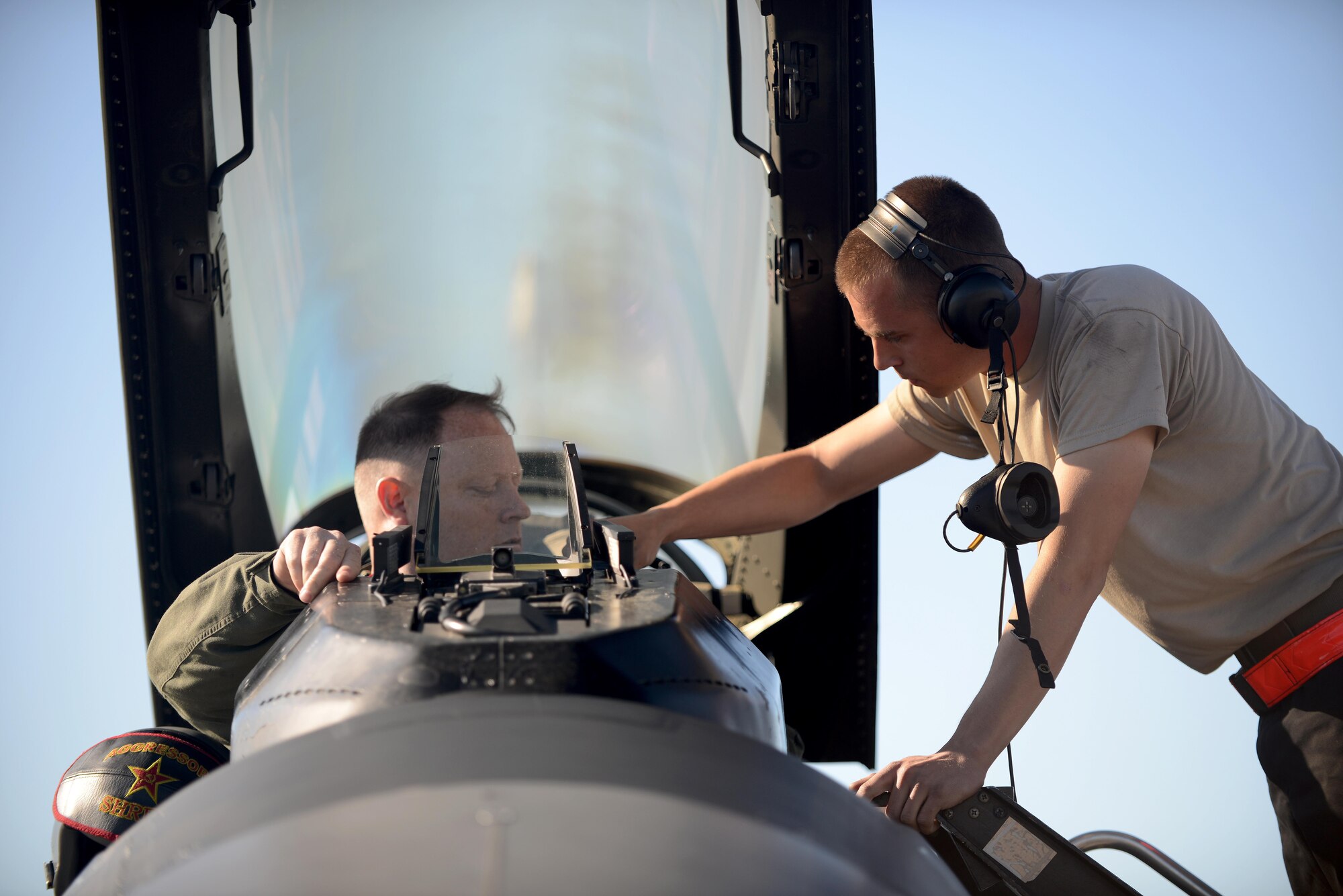 U.S. Air Force Airman 1st Class Michael Brinkmeyer (left), an F-16 Fighting Falcon assistant dedicated crew chief with the18th Aircraft Maintenance Unit, secures U.S. Air Force Maj. Scott Meng, 18th Aggressor Squadron F-16 Fighting Falcon pilot, during RED FLAG-Alaska 16-2, on Eielson Air Force Base, Alaska, June 15, 2016. (U.S. Air Force photo by Tech. Sgt. Steven R. Doty)