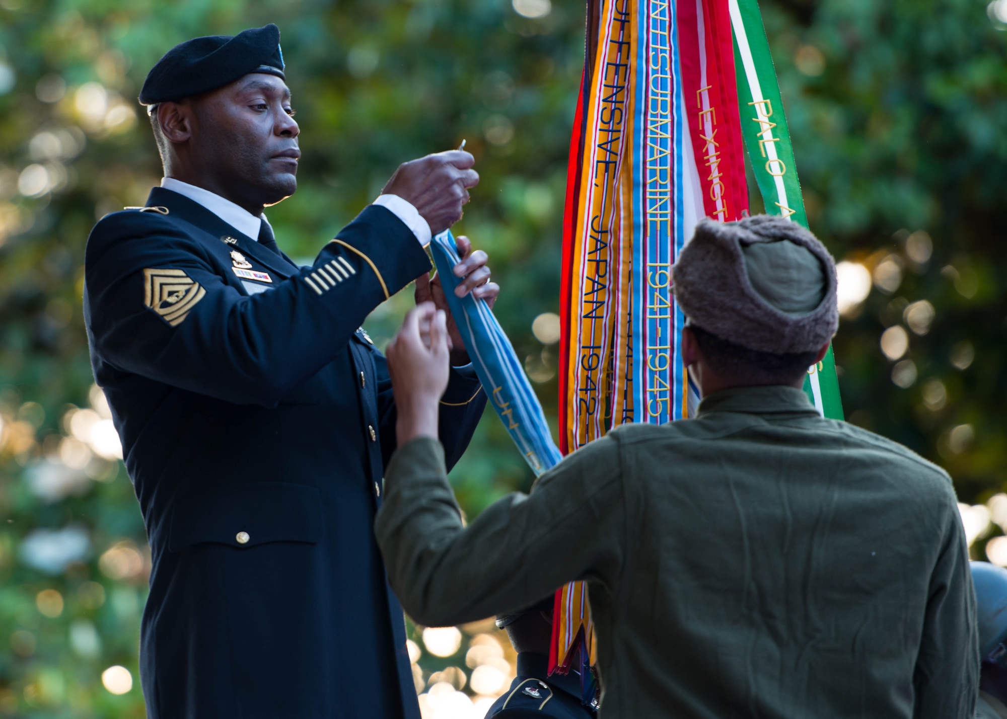 U.S. Army Sgt. Maj. James Jackson, 733rd Mission Support Group command sergeant major, attaches battle streamers to the Army guidon during Music Under the Stars in Magnolia Park at Fort Eustis, Va., June 9, 2016. Each streamer represented a campaign that the Army has fought in, dating from the Revolutionary War to present day. (U.S. Air Force photo by Staff Sgt. J.D. Strong II)
