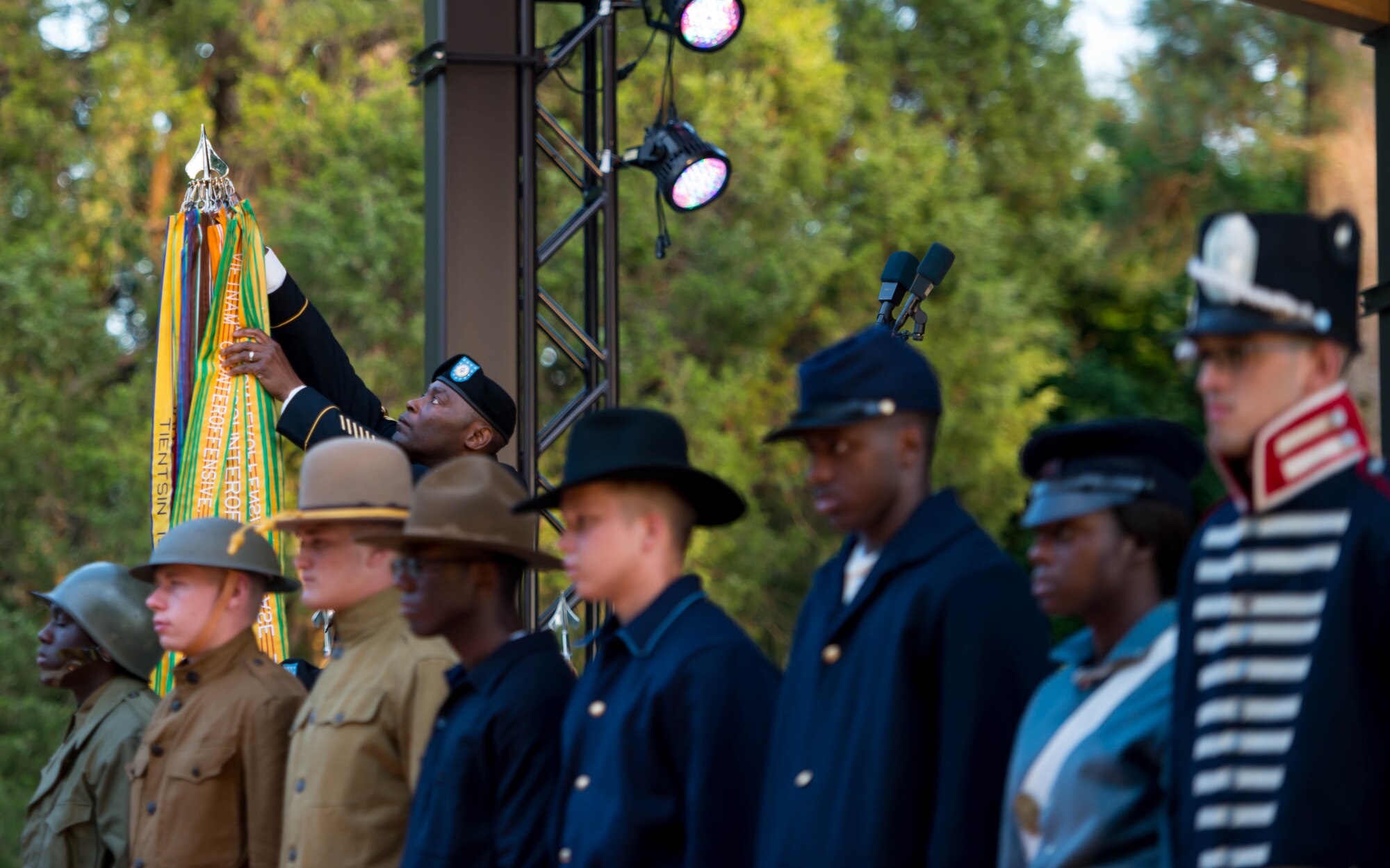 U.S. Army Sgt. Maj. James Jackson, 733rd Mission Support Group command sergeant major, attaches battle streamers to the Army guidon during Music Under the Stars in Magnolia Park at Fort Eustis, Va., June 9, 2016. Each streamer was presented by a soldier in the uniform from the time period the streamer was earned. (U.S. Air Force photo by Staff Sgt. J.D. Strong II)