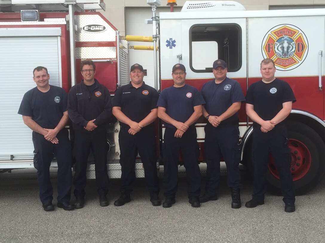 A team of firefighters from the 115th Fighter Wing Truax Fire and Emergency Services pose for a photo outside thier fire truck in Madison, Wis., June 6, 2016. This team of firefighters helped save a woman's life by performing cardiopulmonary resuscitation, a lifesaving technique used when someone's hearbeat has stopped or that person is not breathing. (Photo courtesy of Master Sgt. Gary Peck)