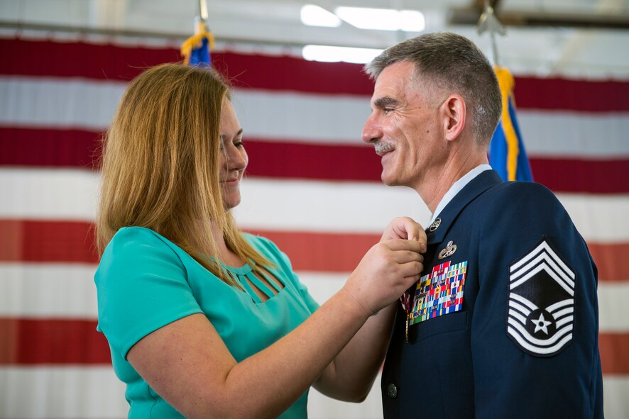 Brittany Brinkley places a retirement pin on the uniform of her father, U.S. Air Force Chief Master Sgt. John Brinkley, 23d Maintenance Group superintendent, during his retirement ceremony, June 10, 2016, at Moody Air Force Base, Ga. Brinkley began his Air Force career as an aerospace ground equipment technician and eventually served in leadership roles such as a first sergeant and superintendent. (U.S. Air Force photo by Airman 1st Class Greg Nash/Released) 