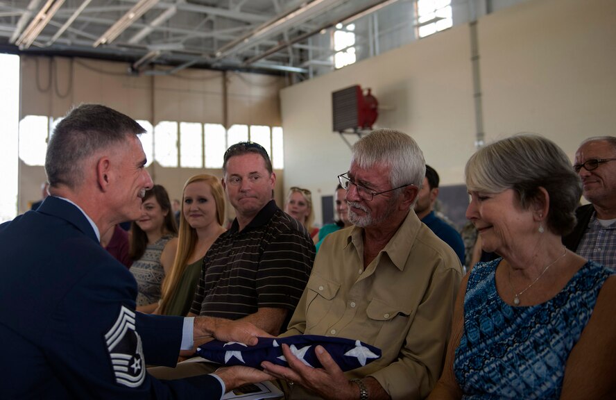 U.S. Air Force Chief Master Sgt. John Brinkley, 23d Maintenance Group superintendent, presents a flag to his father, John, during his retirement ceremony, June 10, 2016, at Moody Air Force Base, Ga. Brinkley joined the Air Force in 1986 as an aerial ground equipment technician. (U.S. Air Force photo by Airman 1st Class Greg Nash/Released)