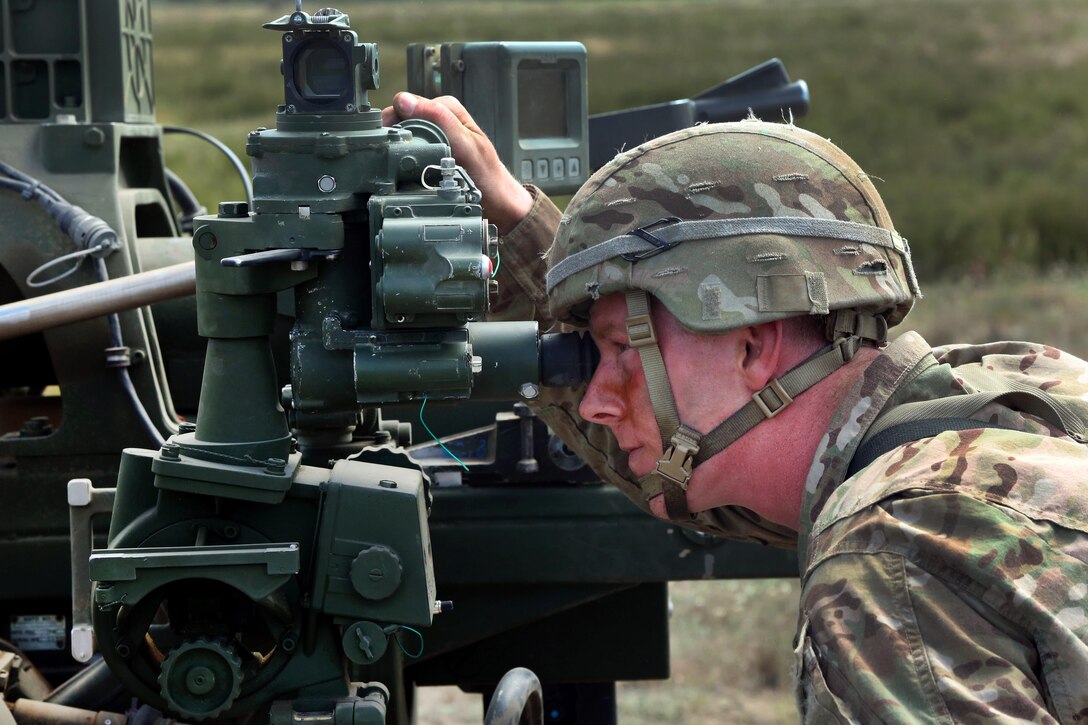 A paratrooper looks through the eyepiece of anM777 howitzer before a fire mission during Anakonda 2016 at Piaskowi drop zone in Drawsko Pomorskie, Poland, June 6, 2016. Army photo by Pfc. Antonio Lewis