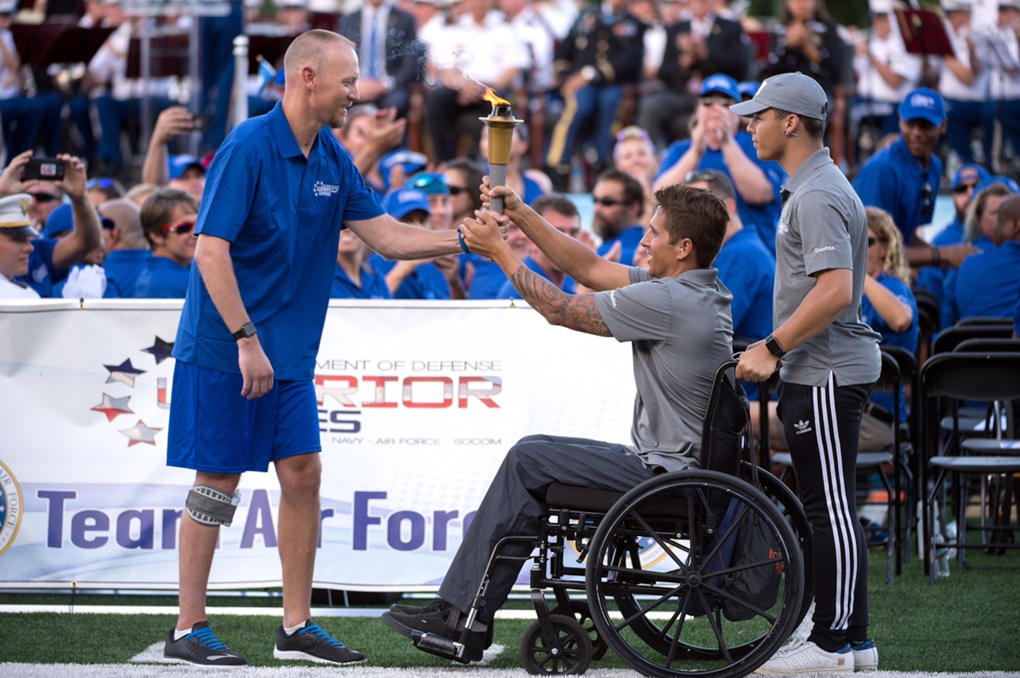 Retired Air Force Capt. Chris Cochrane, left, accepts the 2016 Department of Defense Warrior Games torch from Navy Lt. Ramesh Haytasingh of the U.S. Special Operations Command team during opening ceremonies at the U.S. Military Academy in West Point, N.Y., June 15, 2016. With Haytasingh is his son, Tobias. (Department of Defense photo/EJ Hersom)