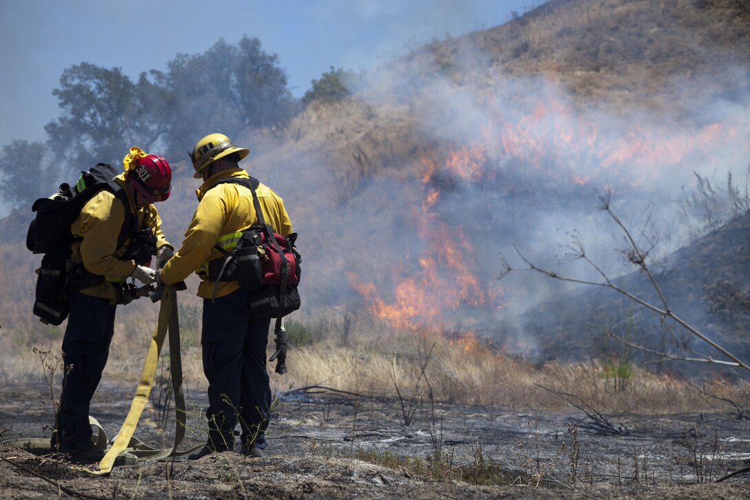 Fire fighters from the surrounding area prepare a hose to fight a fire during fire school on Camp Pendleton, Calif., June 15, 2016. Fire School is run the Camp Pendleton Fire Department to integrate multiple fire departments and develop coordination to better their ability to fight fires together. (U.S. Marine Corps photo by Cpl. Brian Bekkala/MCIWEST-MCB Camp Pen Combat Camera/Released)