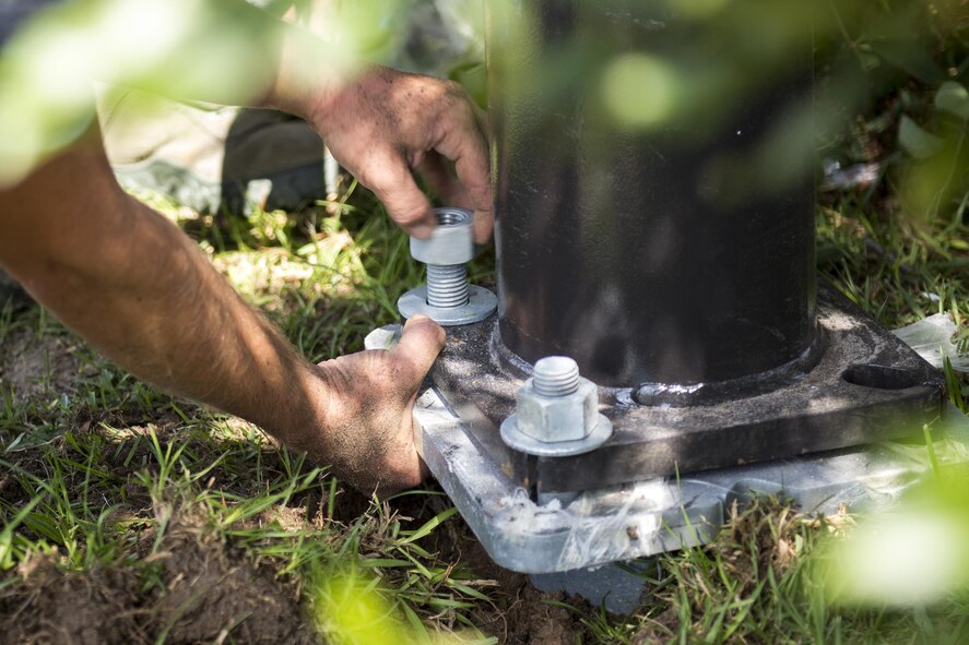 U.S. Air Force Airmen assigned to the 23d Civil Engineer Squadron tighten nuts to secure a new light fixture, June 15, 2016, at Moody Air Force Base, Ga. Communication and steady hands help ensure a light pole is installed properly. (U.S. Air Force photo by Airman Daniel Snider/Released)