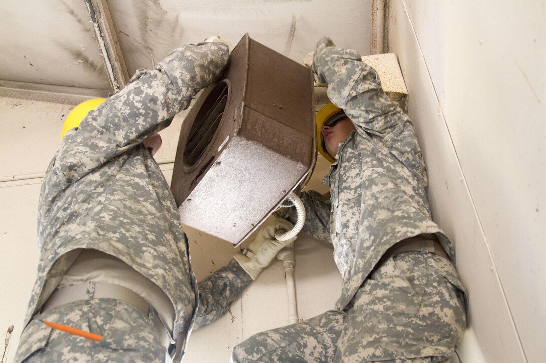 JOINT BASE MCGUIRE-DIX-LAKEHURST, N.J. - Pfc. Nathan Rupert, interior electrician, and Sgt. Mark Kline, carpenter, remove a fan during demolition of a latrine during training exercise Castle Installation Related Construction 2016. The Soldiers are members of the 358th Engineer Company based in New Cumberland, Pa. (U.S. Army photo by Sgt. Anshu Pandeya, 372nd Mobile Public Affairs Detachment)