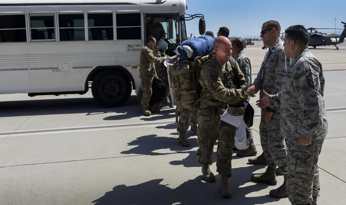 Airmen from the 66th Rescue Squadron and 823rd Air Maintenance Squadron shake the hands as they disembark from a bus after returning from deployment at Nellis Air Force
Base, Nev., June 7. The deployment began approximately four months ago as members of the 823rd MXS and 66th RQS traveled to Afghanistan. (U.S. Air Force photo by Airman 1st Class Kevin Tanenbaum)