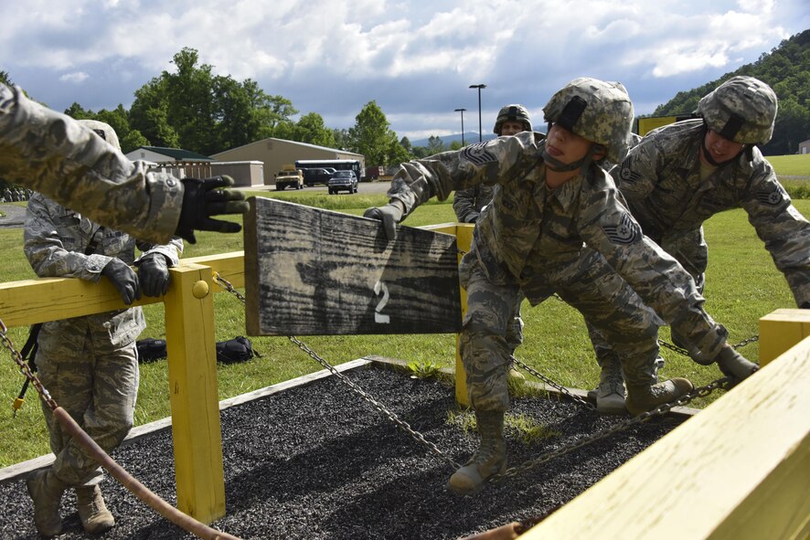 Tech. Sgt. Christina Wick, 911th Aeromedical Staging Squadron medical technician, passes a board to her squad members as she balances herself on a pair of chains during a leadership reaction course at Camp Dawson, West Virginia, June 8, 2016. The leadership reaction course obstacle required the group of medical technicians to get all of its members and supplies from one end to the other without touching the yellow-painted areas or the ground. (U.S. Air Force photo by Staff. Sgt. Jonathan Hehnly)