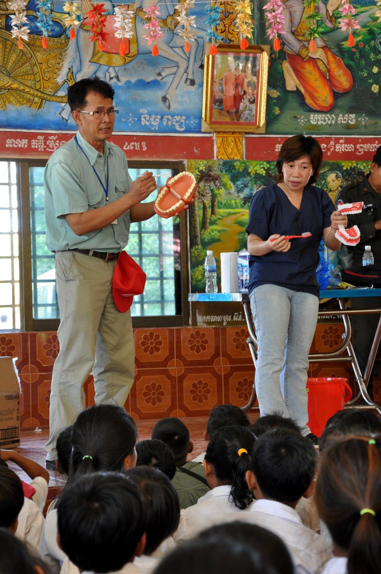 Minh Huong, the lead for the East Meets West - Dental non-governmental organization based in Vietnam, speaks to a group of children on the importance of dental hygiene while Mam Sochenda, a translator for Pacific Angel 16-2 translates her words, June 15, 2016, in Kampot Province, Cambodia. Dental providers from East Meets West, a non-governmental organization based in Vietnam, partnered with U.S., Cambodian, Australian, Vietnamese and Thai military counterparts as part of Pacific Angel 16-2, a multilateral humanitarian assistance/civil military mission, to provide the multitude of children basic dental examinations and, more importantly, educate them on the importance of proper dental hygiene. (U.S. Air Force photo by Capt. Susan Harrington/Released)