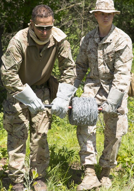 Lance Cpl. Robert L Herpel (right), a combat engineer with Company C, 6th Engineer Support Battalion, 4th Marine Logistics Group, Marine Forces Reserve, and Pvt. Antonio Comparetto (left), a sapper with 131 Commando Squadron Royal Engineers, British army, unwind barbed wire to build a defensive obstacle during exercise Red Dagger at Fort Indiantown Gap, Penn., June 13, 2016. Combat engineers enhance a force’s momentum by physically shaping the battle space to enhance a unit’s use of space and time while denying the enemy unencumbered movement. Exercise Red Dagger is a bilateral training exercise that gives Marines an opportunity to exchange tactics, techniques and procedures as well as build working relationships with their British counterparts. (U.S. Marine Corps photo by Sgt. Ian Leones/Released)