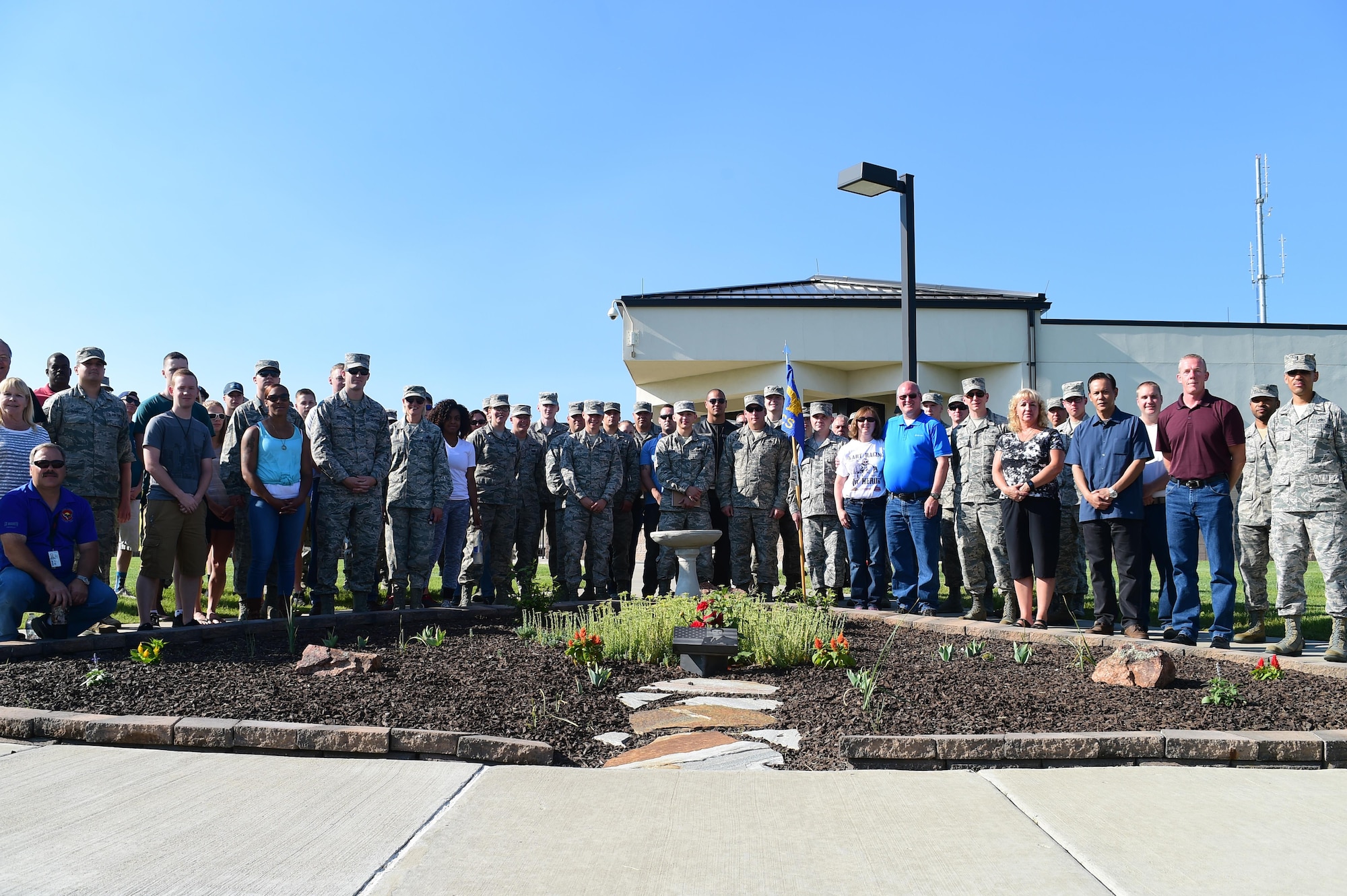 People who attended the Senior Airman Michael S. Snyder memorial ceremony stand together behind his memorial garden June 16, 2016, on Buckley Air Force Base, Colo. Every year, Team Buckley members gather in remembrance of Snyder who was tragically killed by a drunk driver in 2014. (U.S. Air Force photo by Airman 1st Class Luke W. Nowakowski/Released)