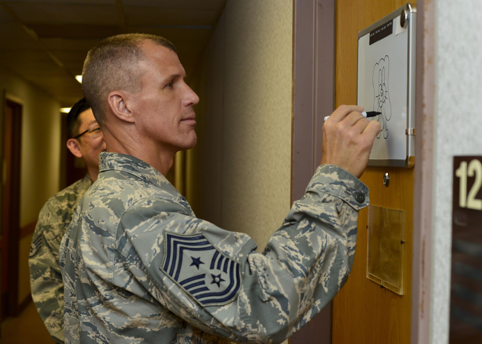 Chief Master Sgt. Steve McDonald, Air Combat Command command chief, draws a picture on a 694th Intelligence Surveillance and Reconnaissance Group Airman’s dormitory door at Osan Air Base, Republic of Korea, June 16, 2016. Part of McDonald’s visit to Osan included a tour of one of the 694th IRSG’s dorms to see the living conditions of its Airmen. (U.S. Air Force photo by Senior Airman Victor J. Caputo/Released)