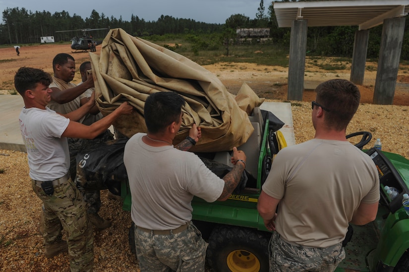 Various support team members prepare to move a fuel tarp during the twentieth iteration of Operation CARAVANA, in Mocorón, Honduras, June 8, 2016. While each member of the support team is an expert in their particular field, what makes the team special is the willingness of each member to help out wherever they are needed while they are living and working in field conditions. Since its initiation, CARAVANA has facilitated the movement of more than 5,000 troops and 225,000 pounds of cargo between remote locations in the eastern part of Honduras, giving the Honduran security teams the ability to quickly focus and adjust their forces against the ever-changing tactics Transnational Criminal Organizations use in the region. (U.S. Air Force photo by Staff Sgt. Siuta B. Ika)
