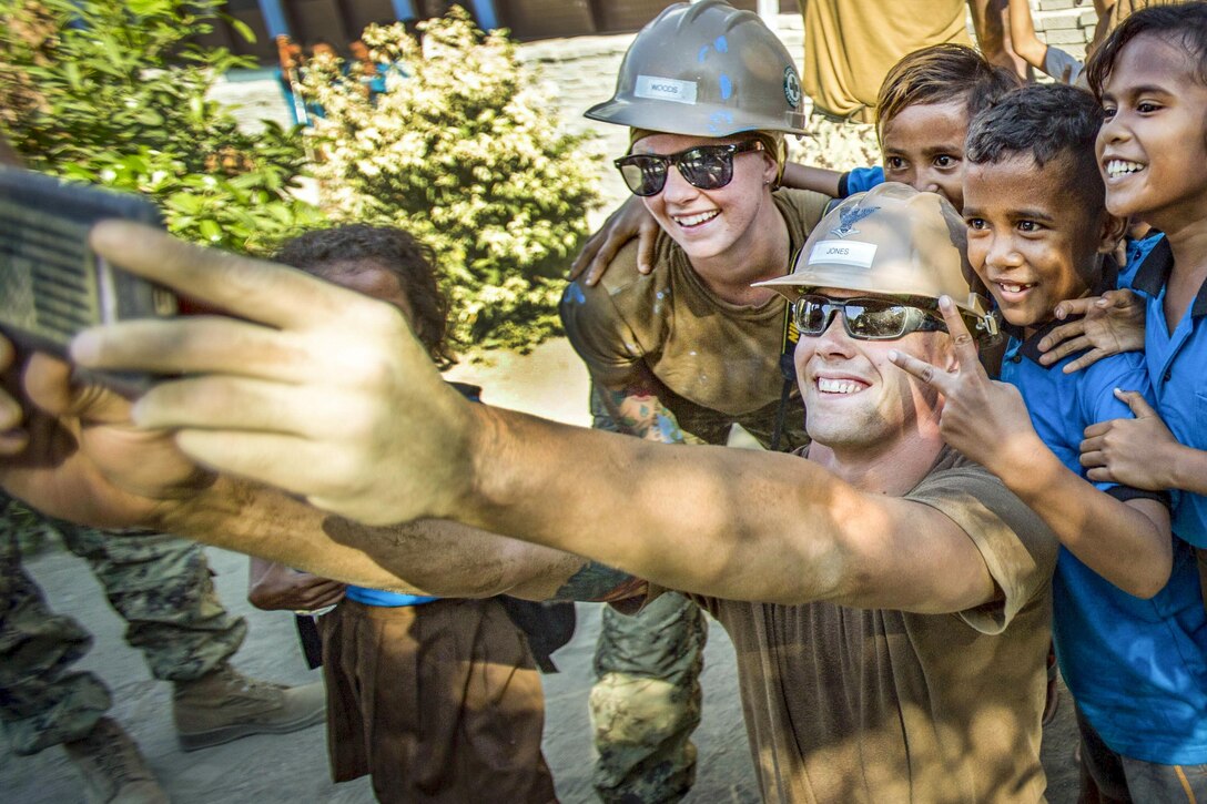 Sailors take a selfie with Timorese children at Aimutin School during Pacific Partnership 2016 in East Timor, June 10, 2016. Marines and Navy Seabees are working alongside Timorese and Australian engineers on various construction projects at Aimutin and Maneluana schools. Marine Corps photo by Cpl. Brittney Vella