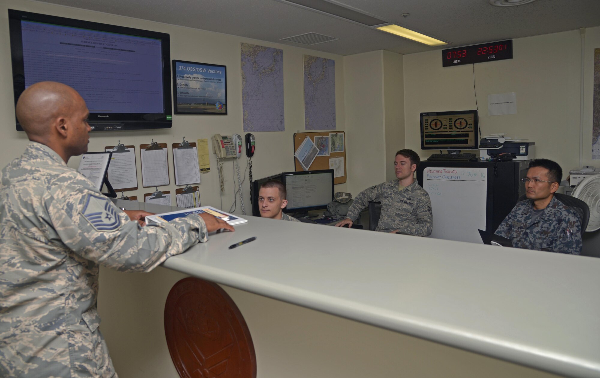 Capt. Naoki Nishino, Japan Air Self-Defense Force weather station forecaster, listens to members of the 374th Operations Support Squadron during a weather briefing at Yokota Air Base, Japan, June 14, 2016. Yokota's weather personnel took Nishino through the flight’s day-to-day operations. (U.S. Air Force photo by Senior Airman David Owsianka/Released)