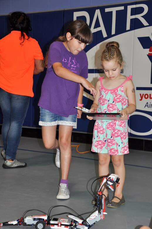 Annika, 8, shows Naylee, 5, how to control a snake built of Legos paired with software so that it would move similarly to a remote control car during the 45th Space Wing’s All SySTEMs Go event June 11, 2016, at the Youth Center/Shark Center at Patrick Air Force Base, Fla. Annika built and programmed the snake herself, and used it to teach other children at the All SySTEMs Go event about science, technology, engineering and math. (U.S. Air Force Photo/Tech. Sgt. Erin Smith/Released)