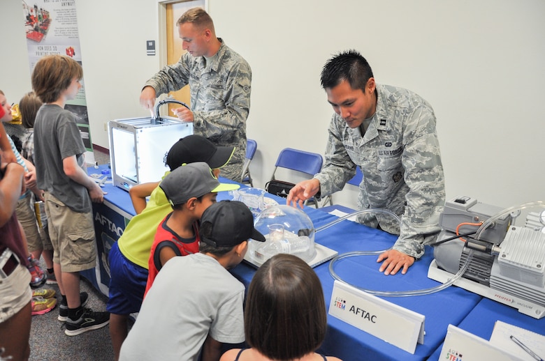Airman Thomas Anastasio, left, a seismic analysist, and Capt. Jonathan Hoang, a chemist, both assigned to Air Force Technical Applications Center, teach children about science and how it ties to space during the 45th Space Wing’s All SySTEMs Go event June 11, 2016, at the Youth Center/Shark Center at Patrick Air Force Base, Fla. The event was designed to teach children of all ages about science, technology, engineering and math. (U.S. Air Force Photo/Tech. Sgt. Erin Smith/Released)