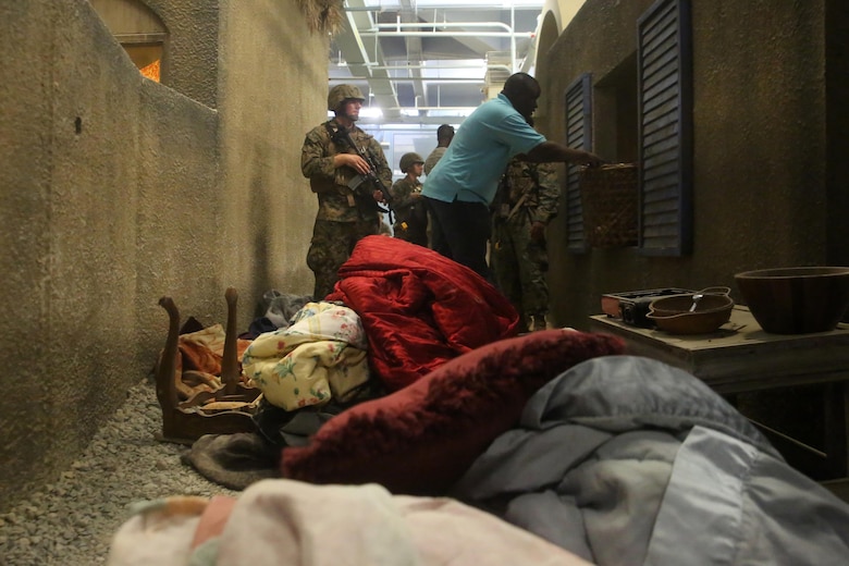 A Marine with 2nd Civil Affairs Group and a role player stand in an alley of a notional West African village during a training exercise that integrated 2nd CAG and II Marine Expeditionary Force at Camp Lejeune, N.C., June 12, 2016. The training was designed to have the civil affairs specialists assess the damages and needs of villagers in a war-torn environment. (U.S. Marine Corps photo by Cpl. Joey Mendez/Released)